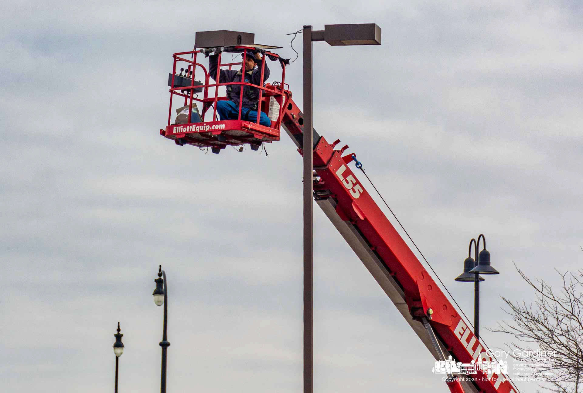 An electrician removes a sodium vapor light fixture at the Westerville Center shopping center to replace it with new LED fixtures. My Final Photo for November 29, 2022.