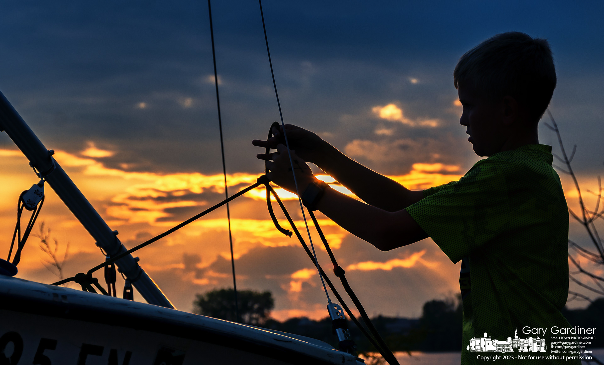A young sailor ties off the lines on his boat after finishing training races at Hoover Reservoir Thursday at sunset. My Final Photo for September 7, 2023. 