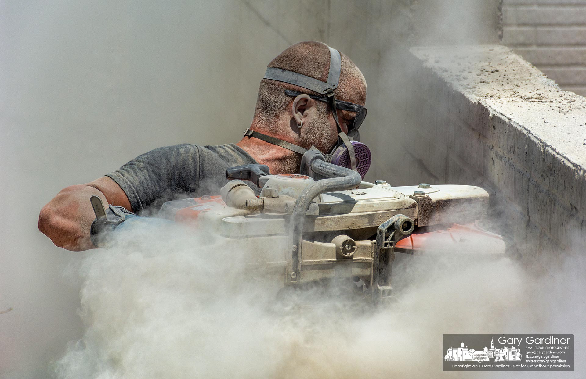 A contractor works through a cloud of dust thrown from the concrete wall he's cutting on a newly poured wall at a home under construction on East Walnut St. My Final Photo for June 29, 2021.