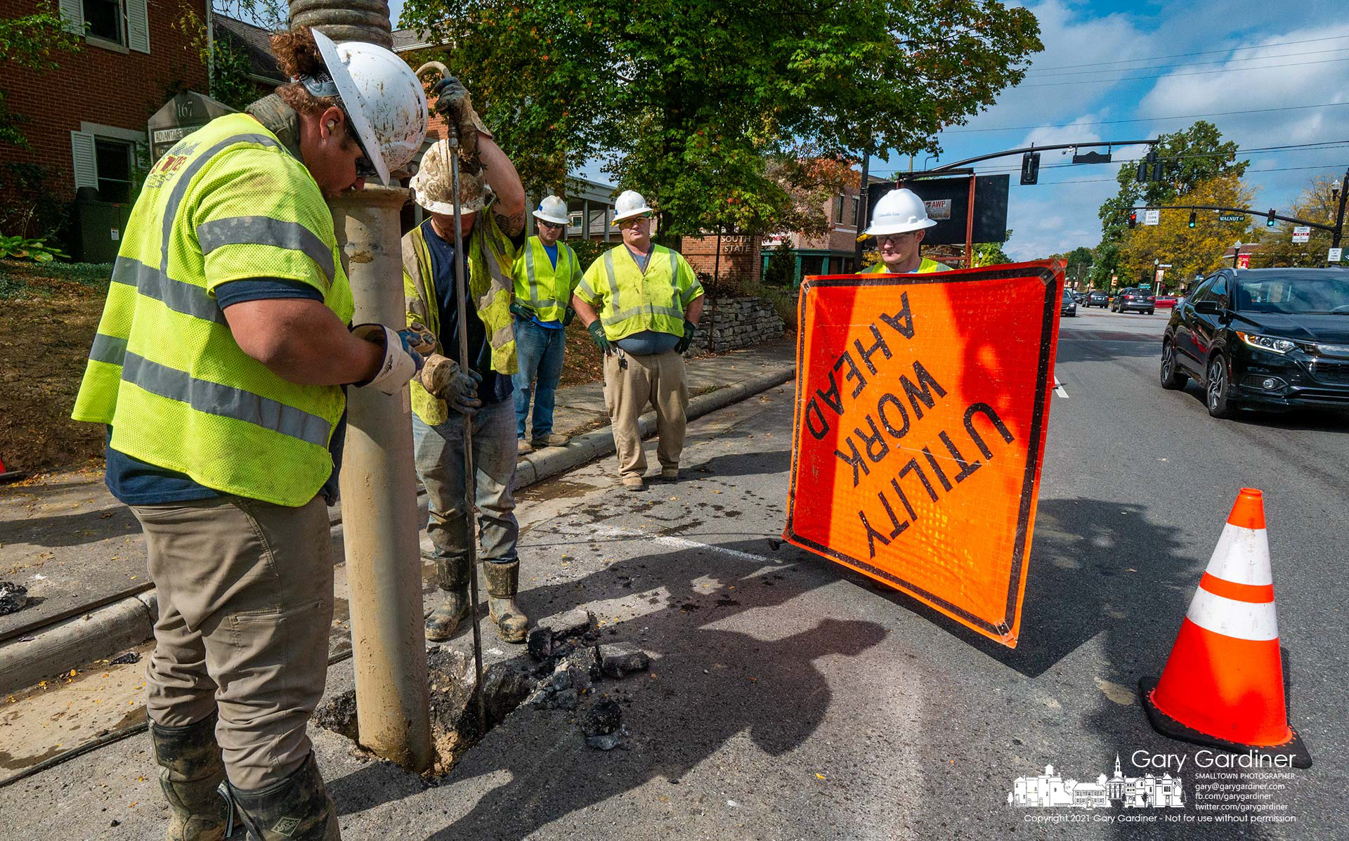 A work crew vacuums debris from a hole cut into State Street near Walnut Street where a pressure cutter cuts away the road to expose a gas line that needs repair. My Final Photo for Oct. 8, 2021.