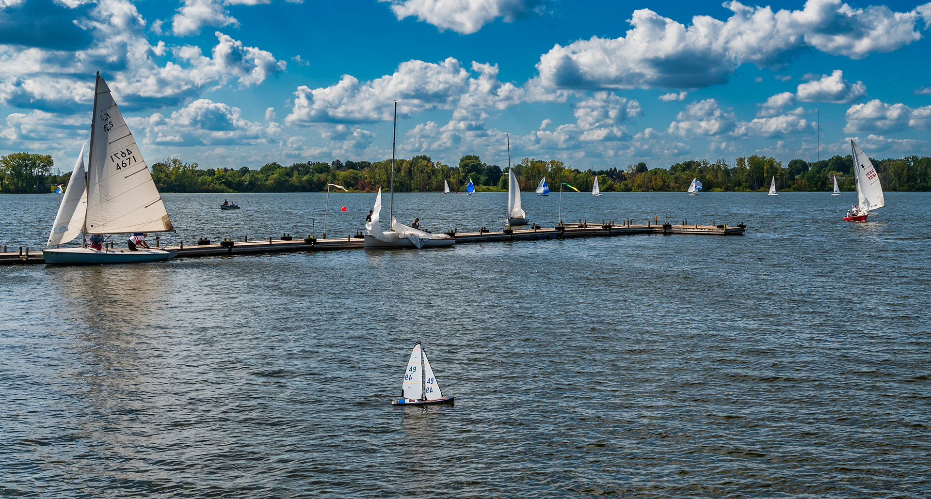 An electric-powered model sailboat travels past its larger cousins as it navigates the waters near the shoreline and docks at Hoover Sailing Club on Hoover Reservoir. My Final Photo for September 3, 2023. 