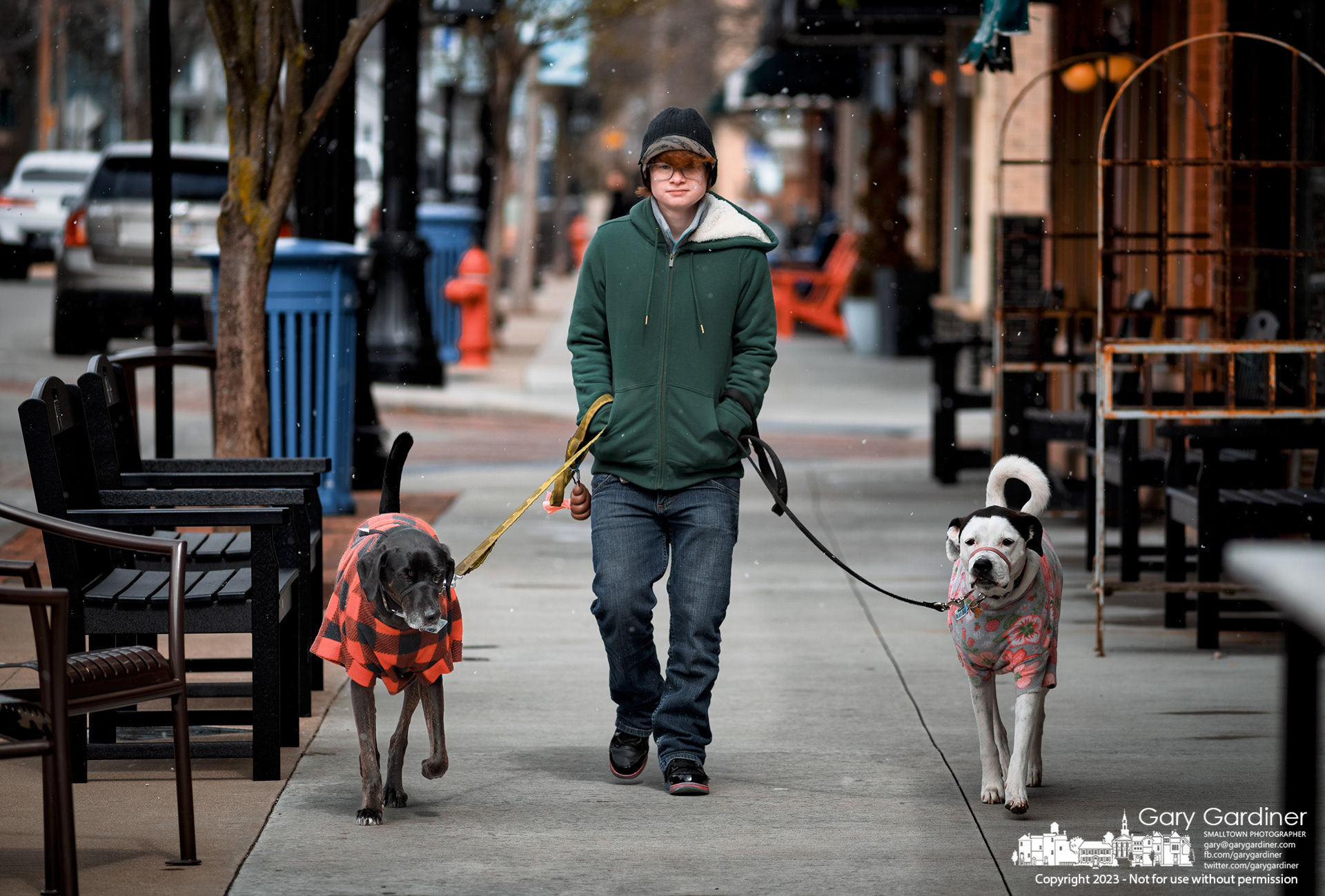 A pair of dogs and their walker wear warm coats as they take a fast stroll into the wind and snow flurries in Uptown Westerville Saturday afternoon. My Final Photo for March 28, 2023.