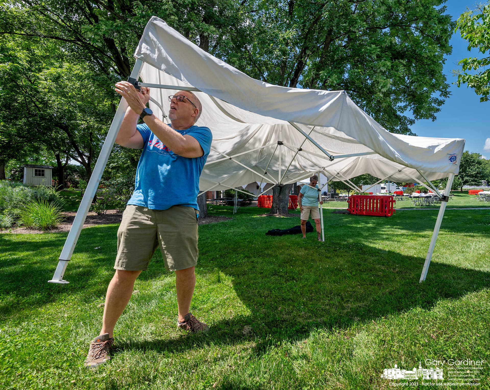 An artist's helper gives extra pressure to secure a popup tent pole as he and others set up spaces in Heritage Park for the weekend's Westerville Music and Arts Festival. My Final Photo for July 7, 2023. https://bit.ly/43kOIKm