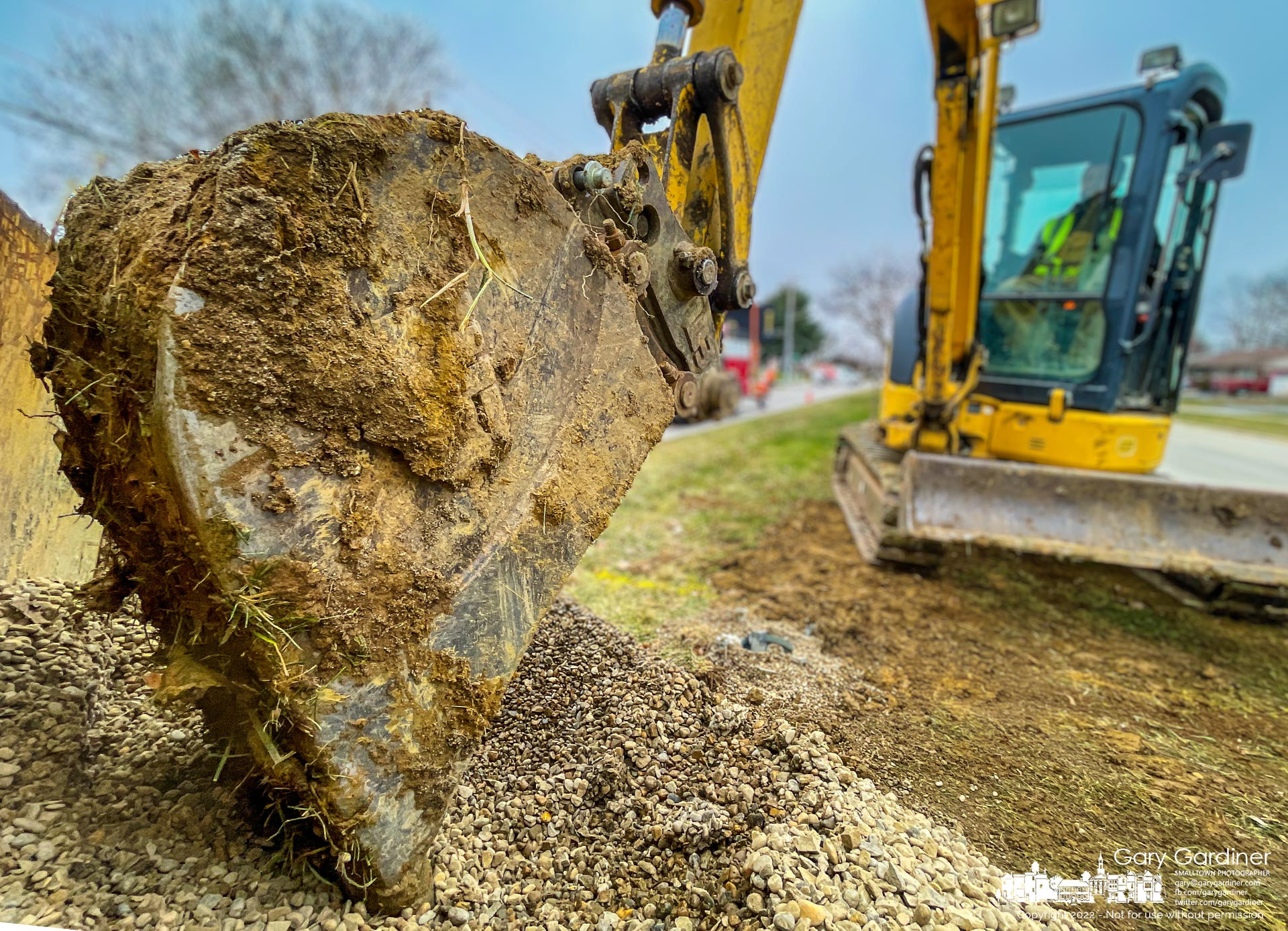 Gravel is pushed into a hole dug in the Huber Village Boulevard median to connect underground conduit to anchors for new light poles for the street. My Final Photo for Jan. 6, 2021.