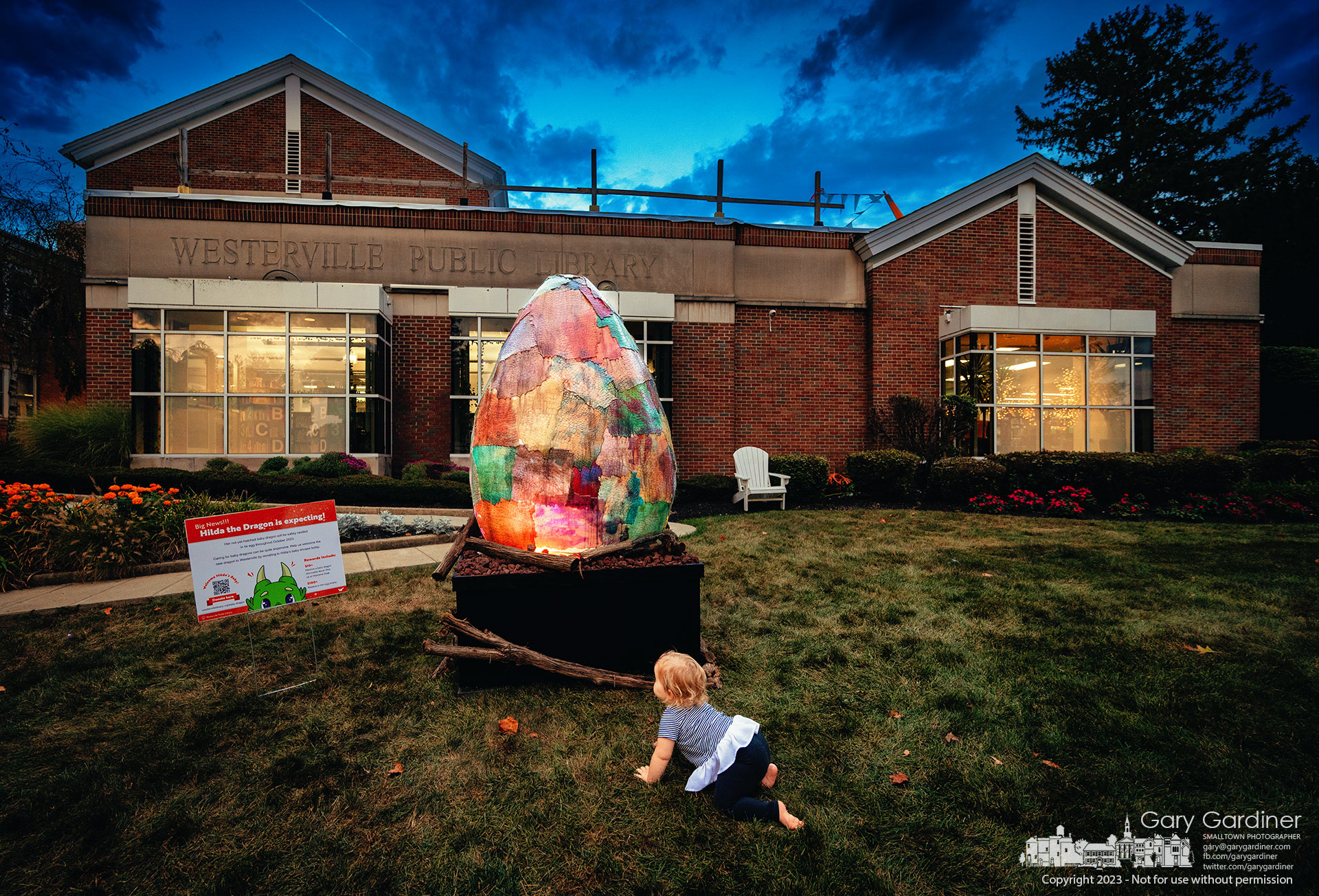 A toddler crawls her way to the glowing Hilda the Dragon egg decorating the front lawn of the Westerville Public Library for Wizards and Wands in October. My Final Photo for October 4, 2023. 