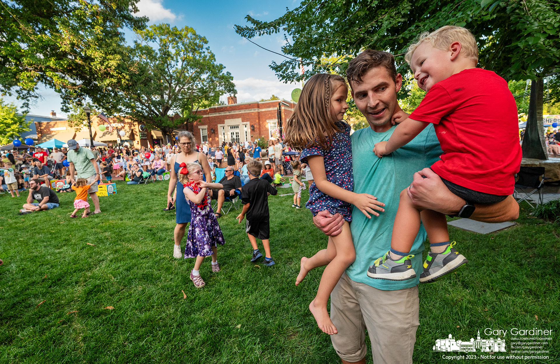 A father spins his children to the rhythm of the band playing in front of city hall during the Fourth Friday street fair in Uptown Westerville. My Final Photo for August 25, 2023.