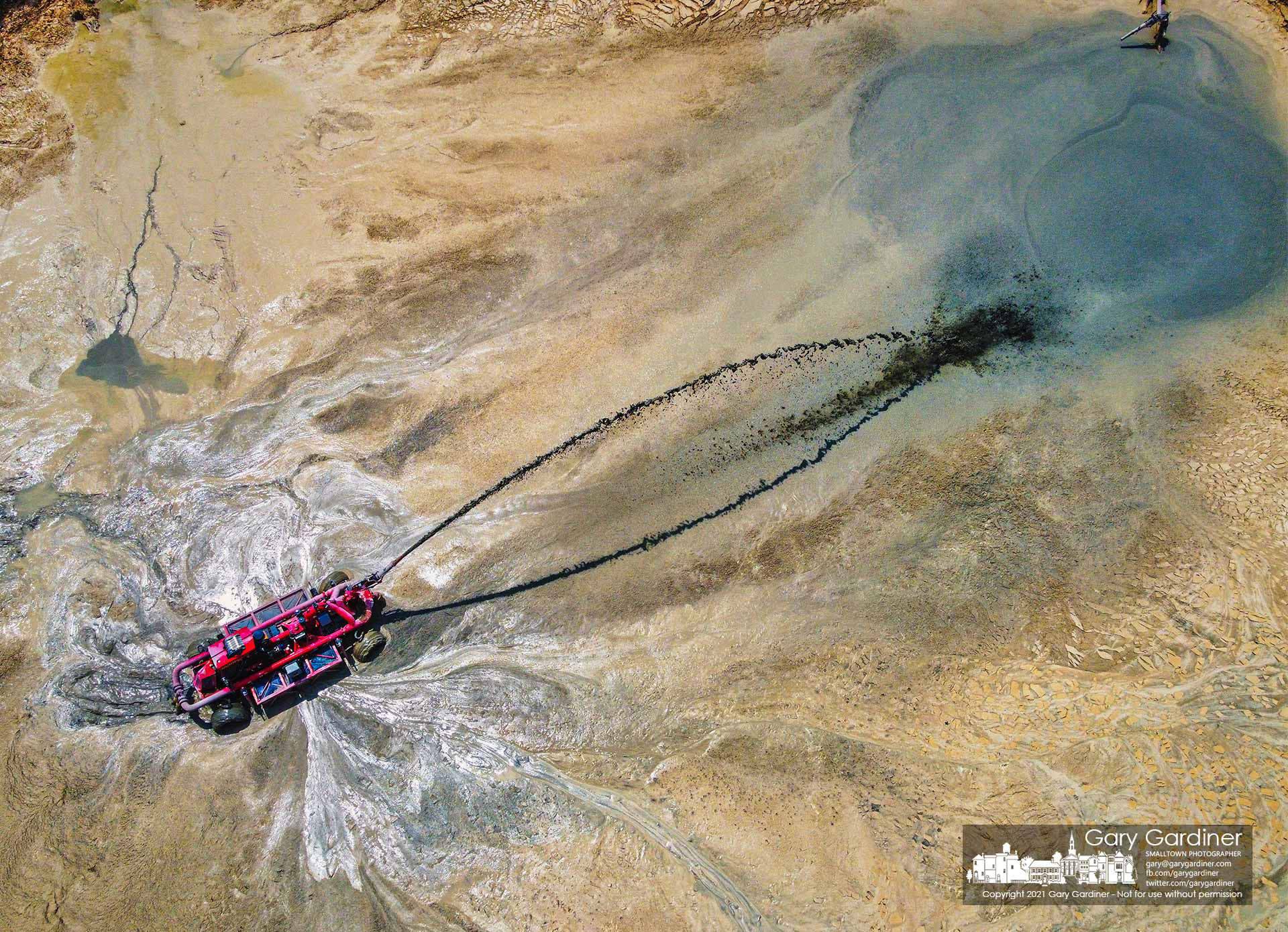 A four-wheel steered remote-controlled pumper throws lime sludge toward an auger that pumps it from the Westerville water plant holding pond to truck tankers that transfer it to farm fields east of New Albany. My Final Photo for July 24, 2021.