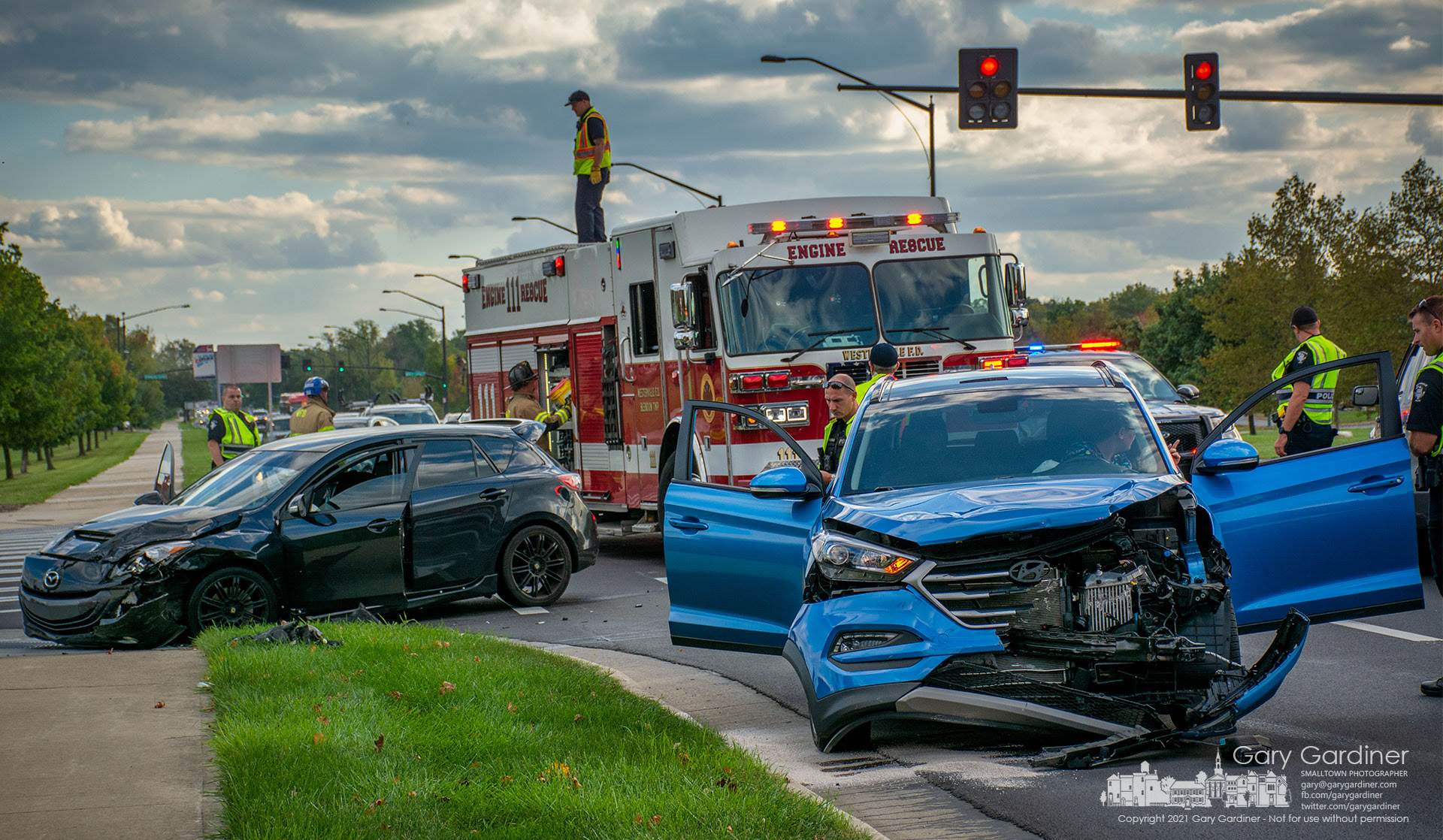 A Westerville firefighter retrieves equipment from the top of a fire truck as police investigate a car crash during rush hour at Cleveland Ave. and County Line Road. My Final Photo for Oct. 12, 2021.