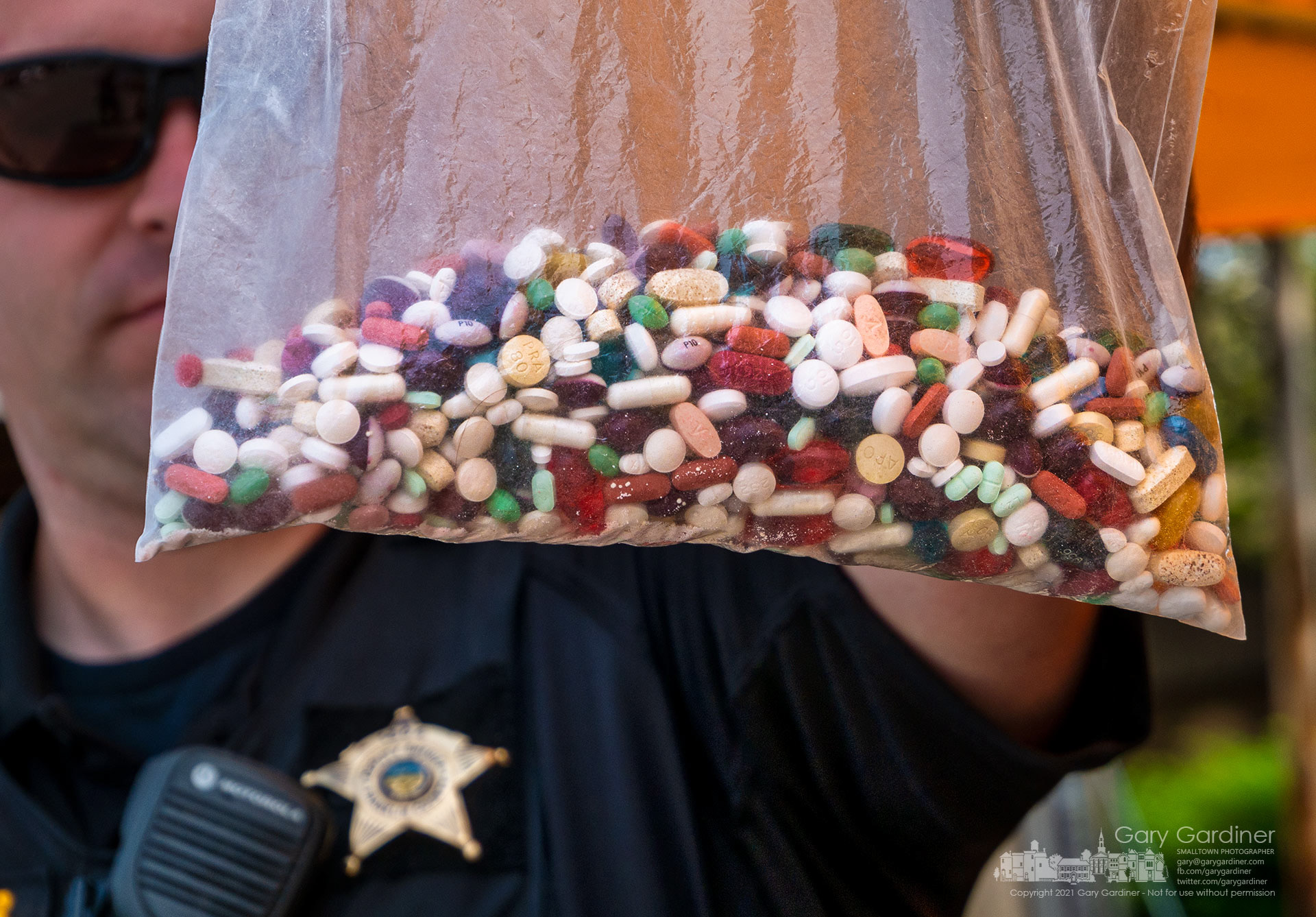 A Franklin County Deputy Sheriff holds a plastic bag containing unused, expired, or not needed prescription and over-the-counter drugs dropped off in the drive-thru at the Kroger on Schrock Road during Saturday’s event sponsored by the Ohio Attorney General. My Final Photo for July 31, 2021.