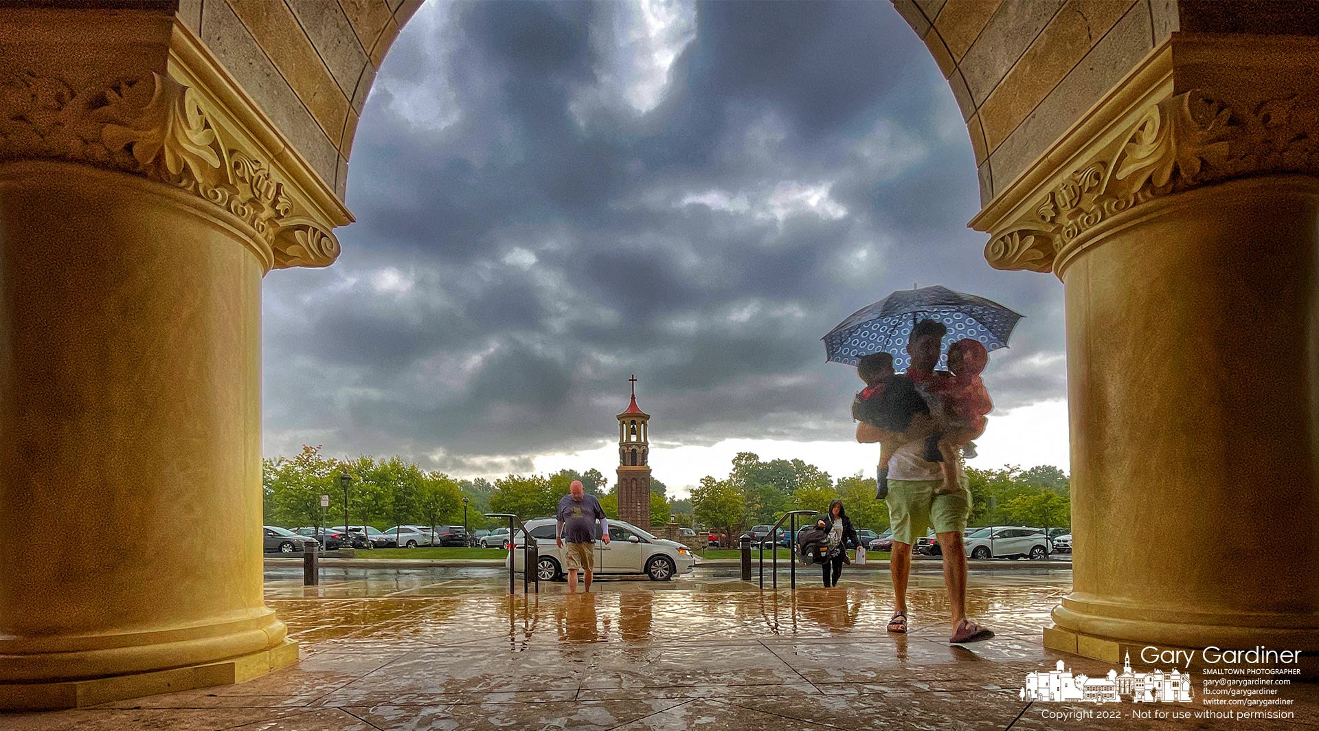 A father carries an umbrella and two of his children as they arrive for early Mass at St. Paul the Apostle Catholic Church during a rainstorm. My Final Photo for Sept. 4, 2022.