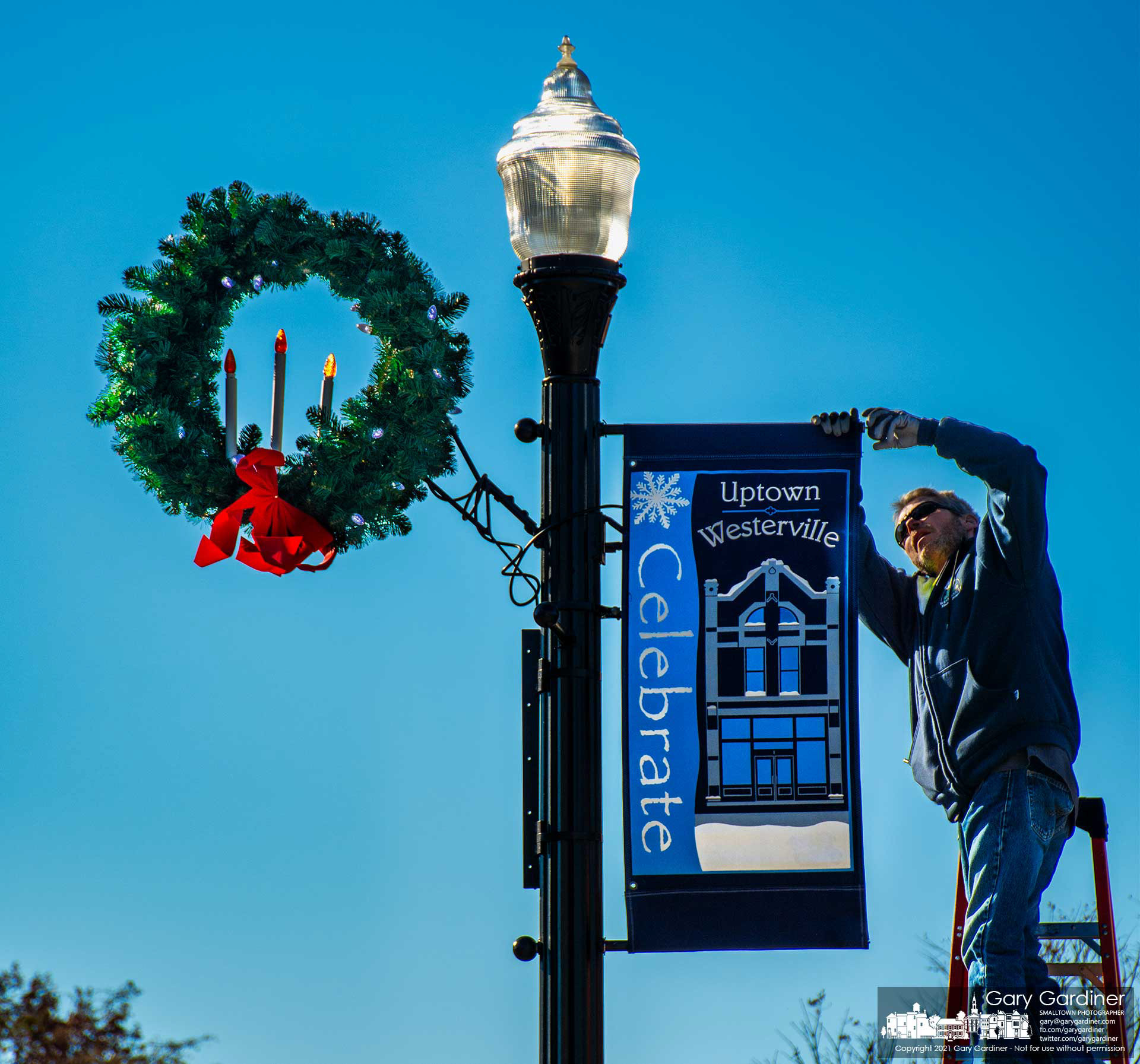 City electric workers install wreaths and holiday banners on streetlights in Uptown Westerville preparing the city for Friday's tree lighting ceremony. My Final Photo for Nov. 30, 2021. 