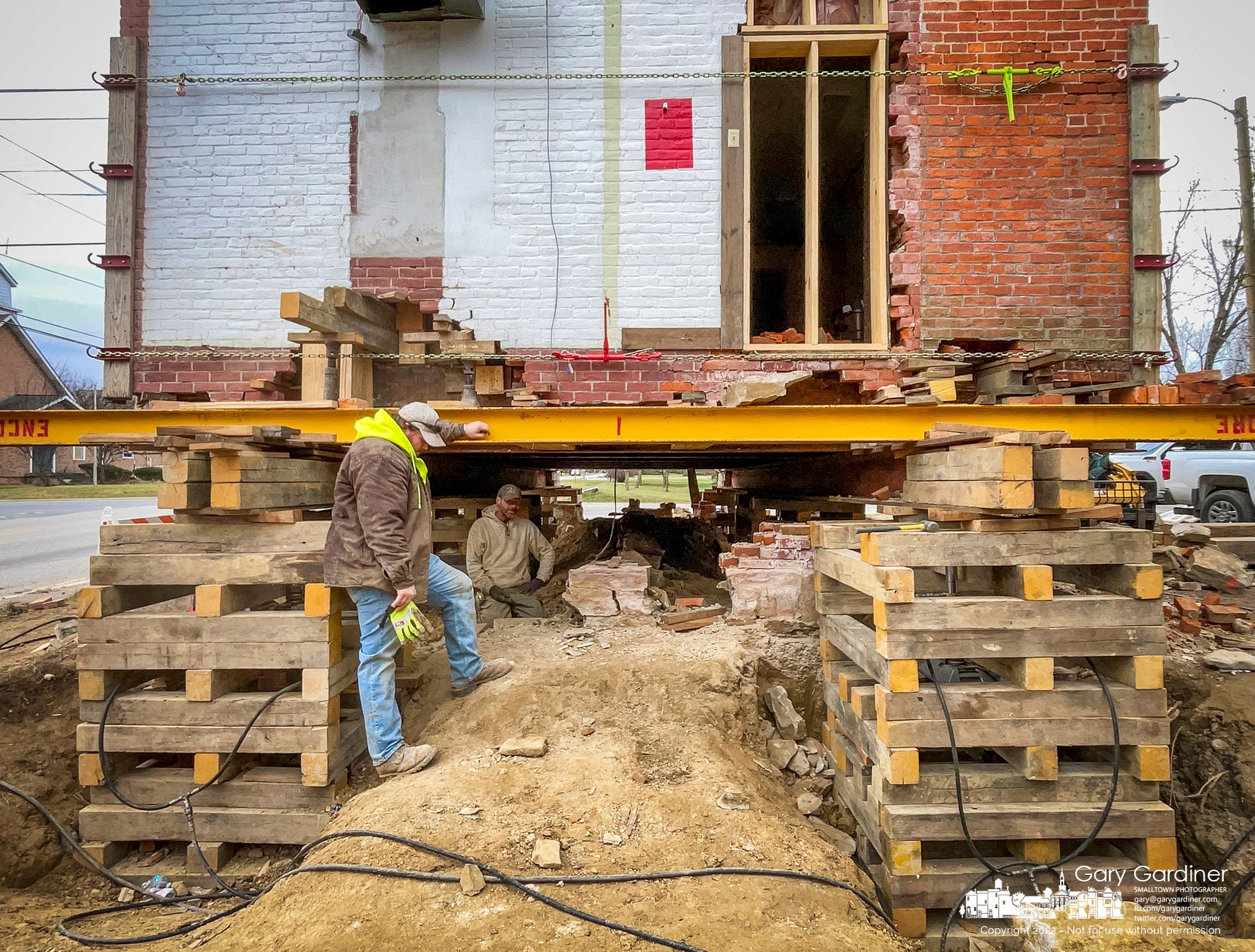 Workers take a break after lifting the old Genoa Town Hall about three feet off the ground as they prepare to raise ti higher and move it next week from its original location to McNamara Park less than a mile away. My Final Photo for December 14, 2022.