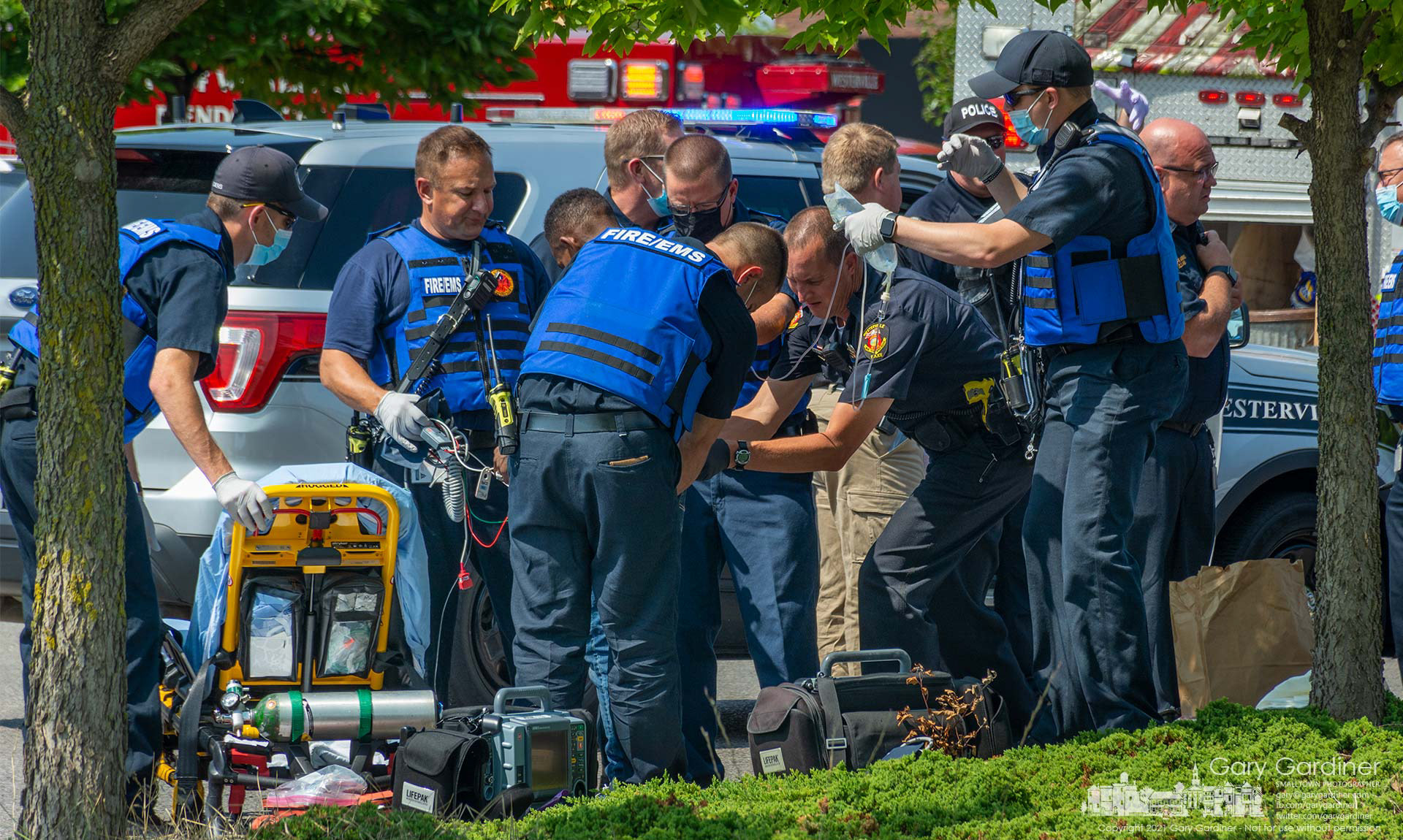 A Westerville police officer searches a man being treated for a stab wound by fire department medics after a fight in a shopping center parking lot Monday morning. My Final Photo for Aug. , 2021.
