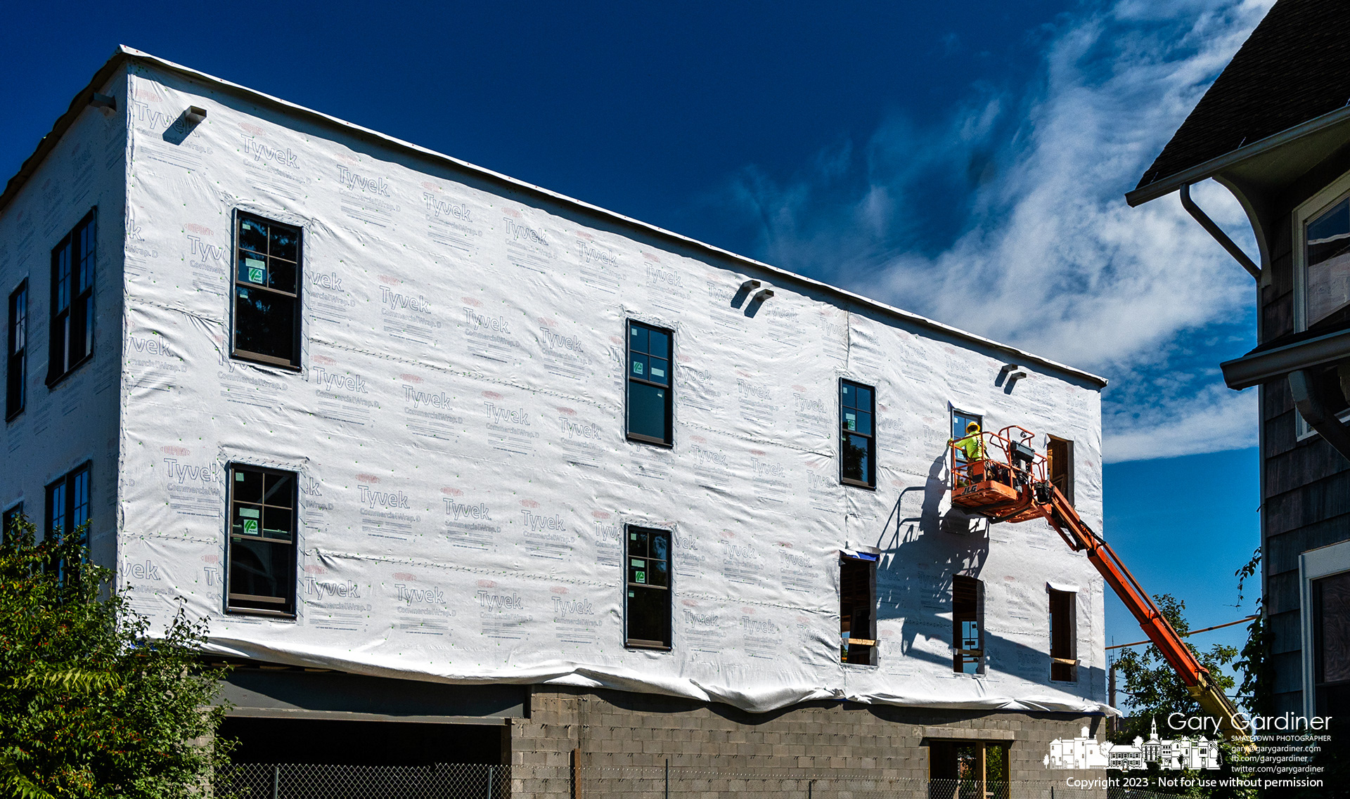Workers install windows in the upper floor apartments of a building being built on West College where the Book Harbor once stood. My Final Photo for September 20, 2023. 