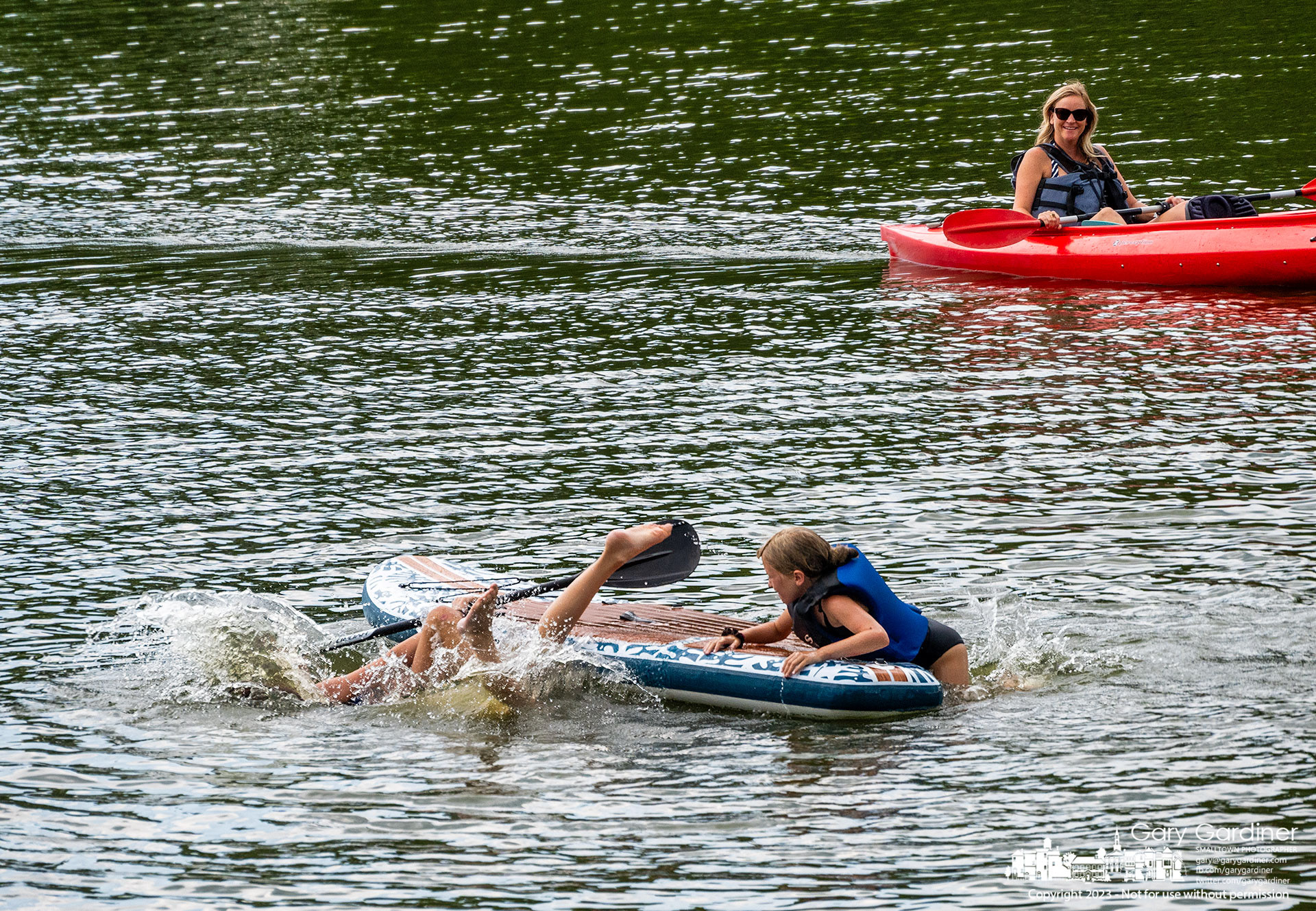 A trio of young girls take turns being the queen of the paddleboard before tossed into the waters of Hoover Reservoir near the Oxbow boat ramp. My Final Photo for July 23, 2023. 