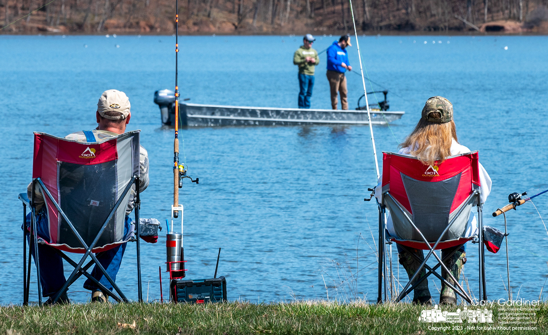A landlocked pair of anglers watch their waterborne partners navigate the waters of Hoover Reservoir on a war, brightly lit spring Sunday. My Final Photo for March 26, 2023.