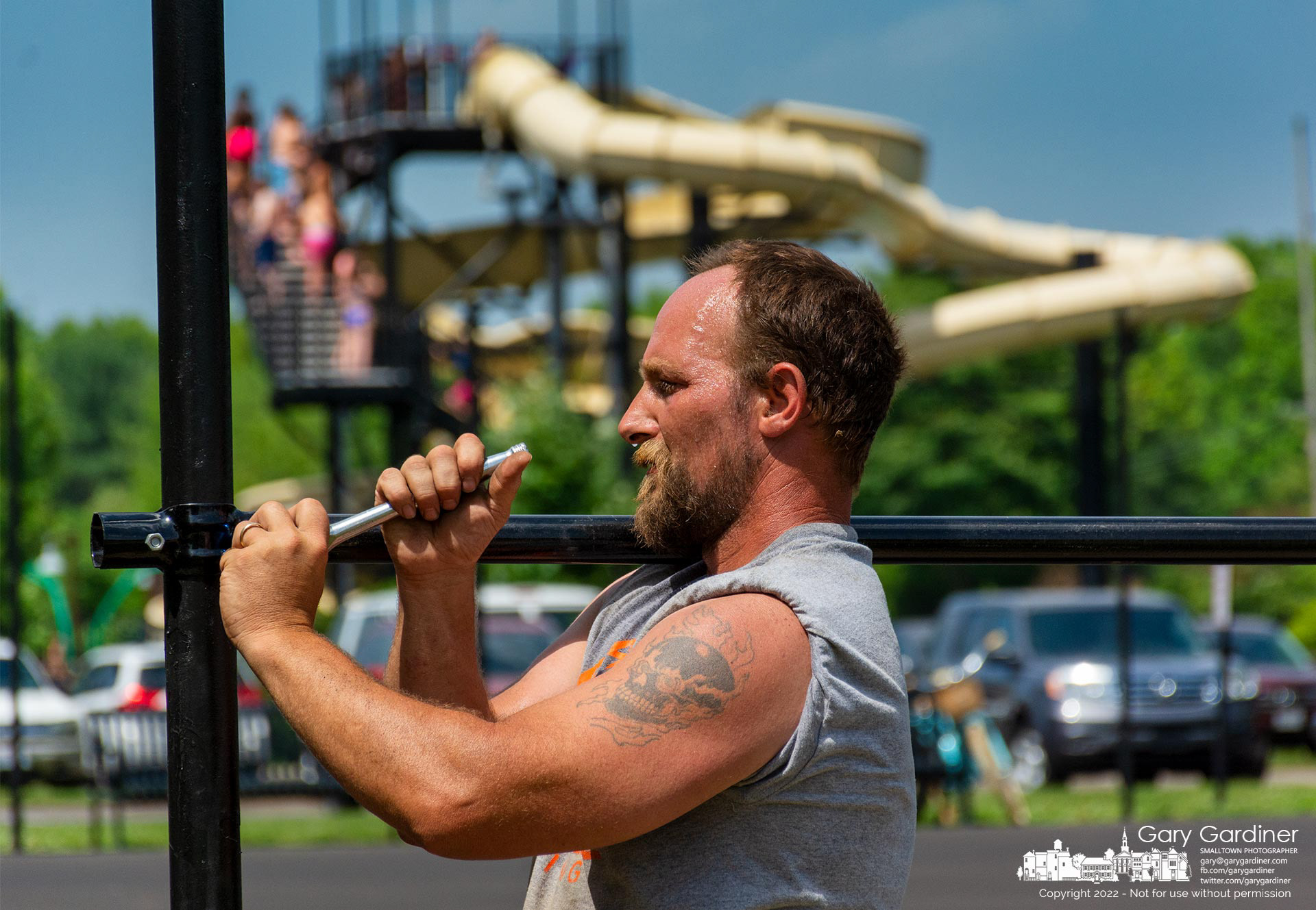 A drop of sweat hangs from the nose of an installer putting fencing around the refurbished tennis courts behind the slide at Highlands Aquatic Center. My Final Photo for June 15., 2022.