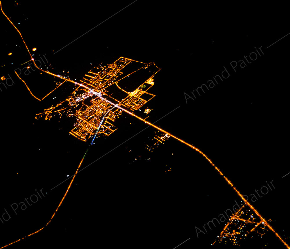 Une ville des Emirats Arabes Unis, éclairée la nuit, au milieu du désert.