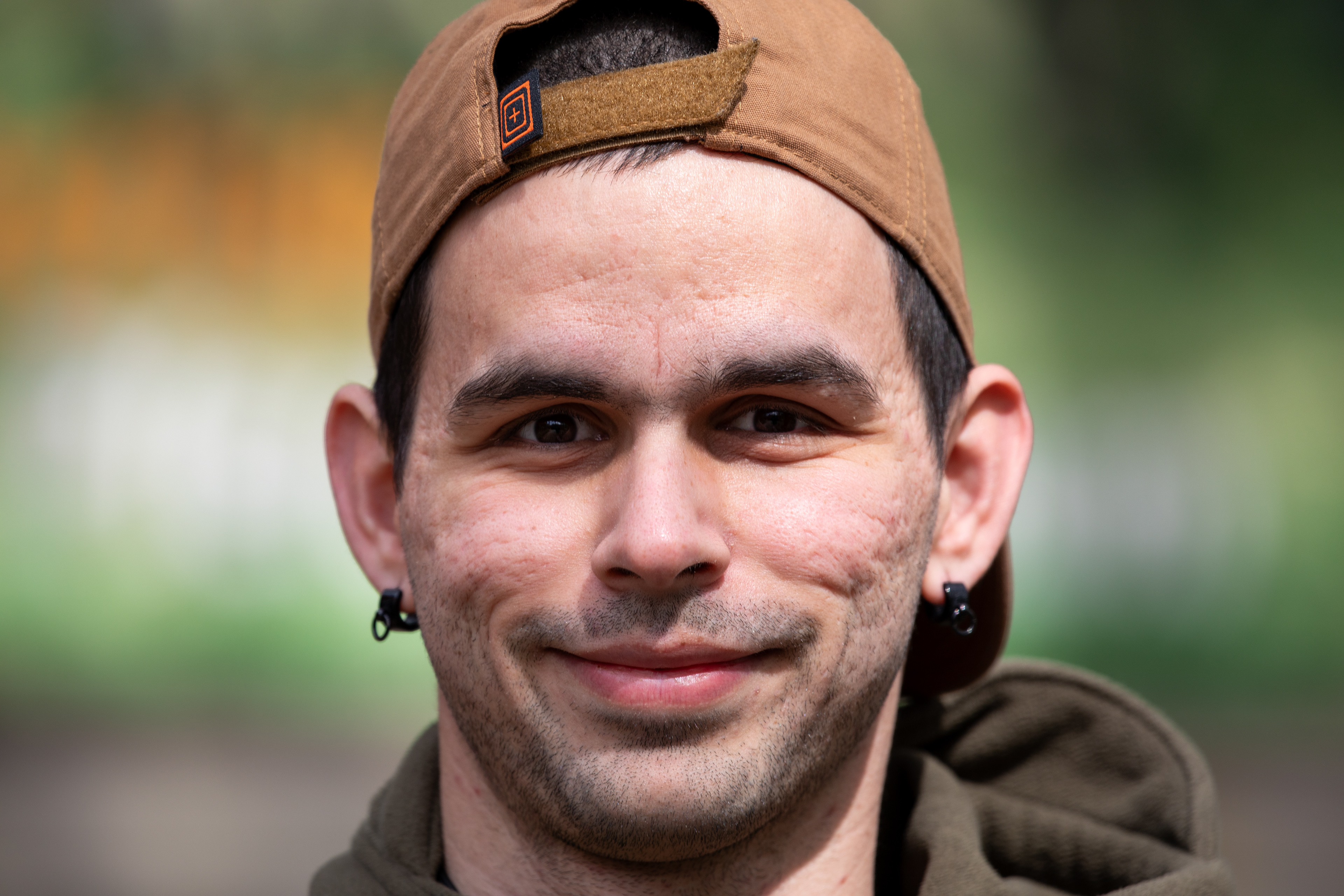 Enrico Sanchez von EKOSphotography mit Mütze im Park. Portrait-Foto mit Bokeh-Hintergrund