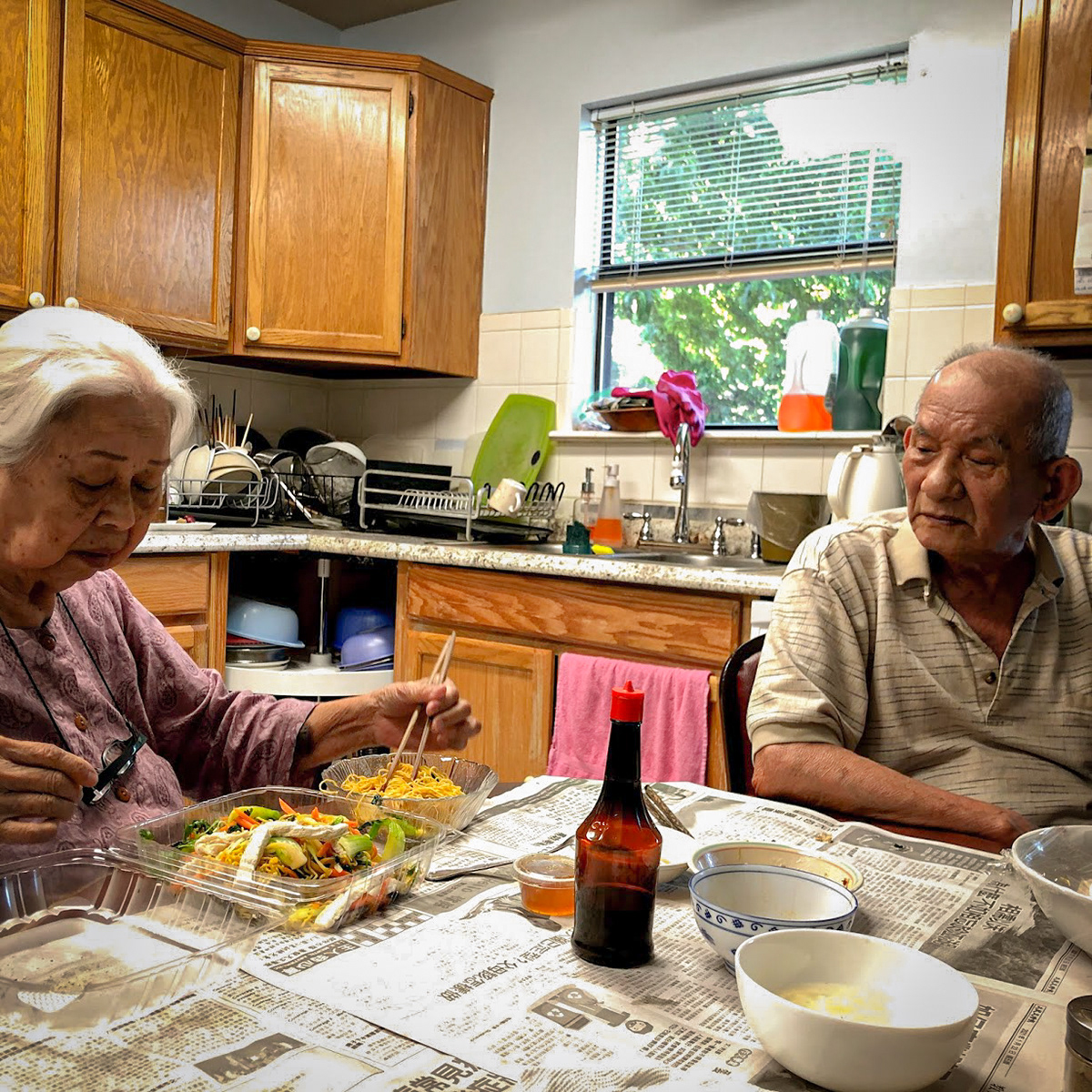 Vietnamese immigrant grandparents sharing lunch in kitchen.