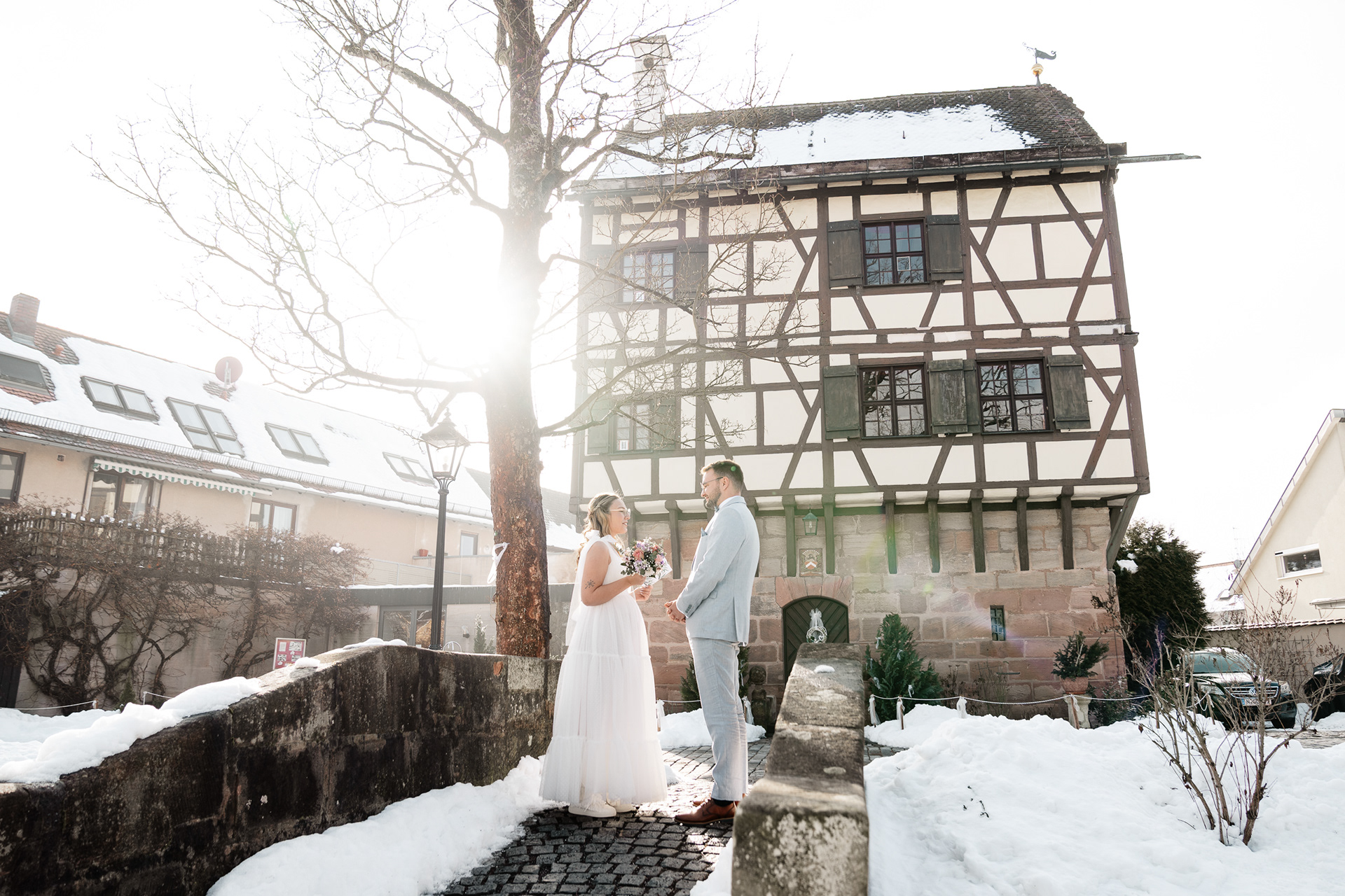 Brautpaar im Schnee vor einem Fachwerkhaus, Hochzeitsfotograf Roth und Nürnberg