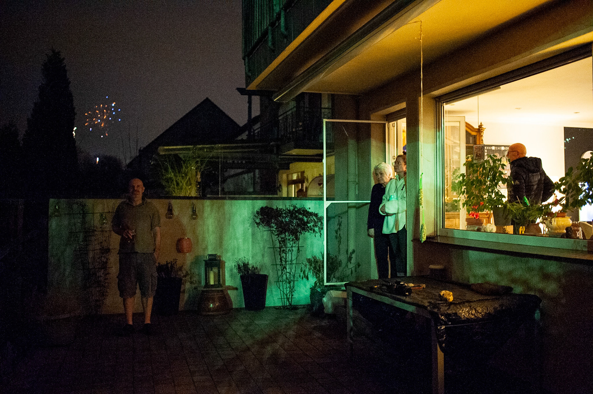 Mom, dad, and Ann-Kristin watch the New Year’s Eve fireworks from the living-room while Christoph stands on the patio. Oberhausen, Germany, January 1, 2023.