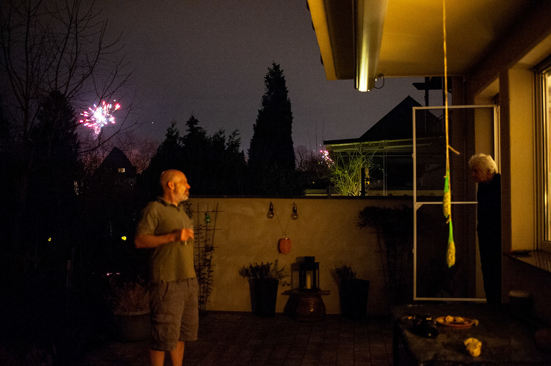 Christoph watches the New Year’s Eve fireworks from the patio while mom looks out the door to the patio. Oberhausen, Germany, January 1, 2023.