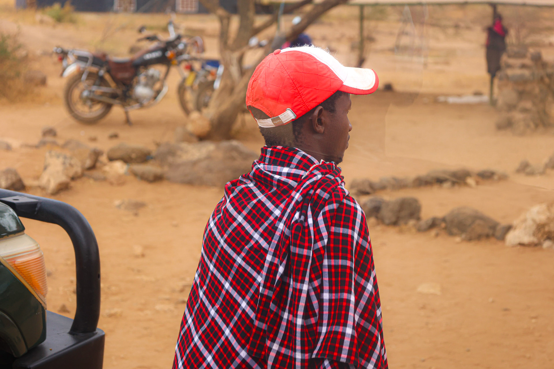 Before entering the vastness of Amboseli Park, the subtle profile of a village resident captures the essence of local life. Draped in a traditional African scarf that cascades over his shoulder, he stands as a silent testament to the region's rich culture and heritage.