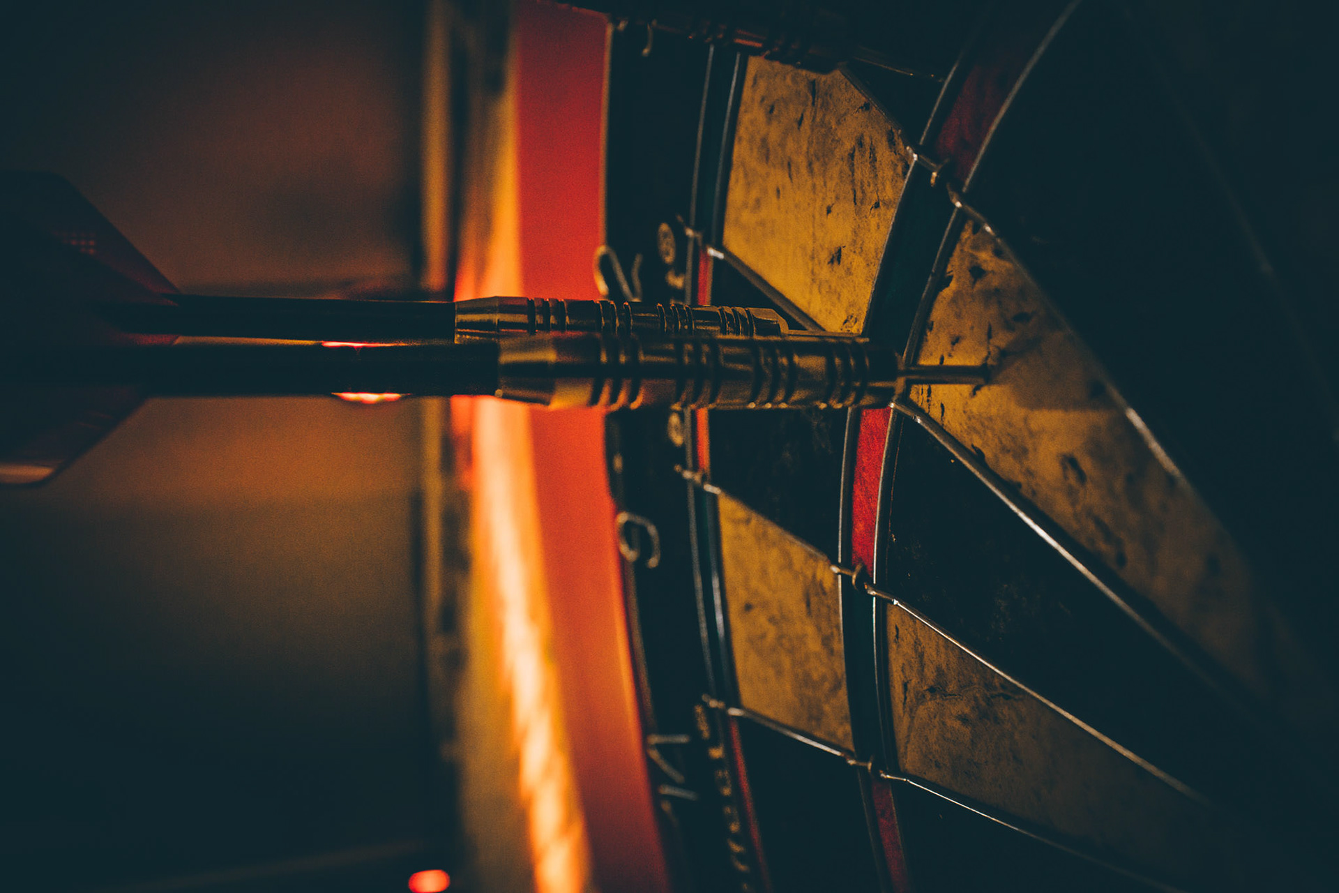 Darts Precision Shot – Close-up of dart hitting the bullseye under warm light.