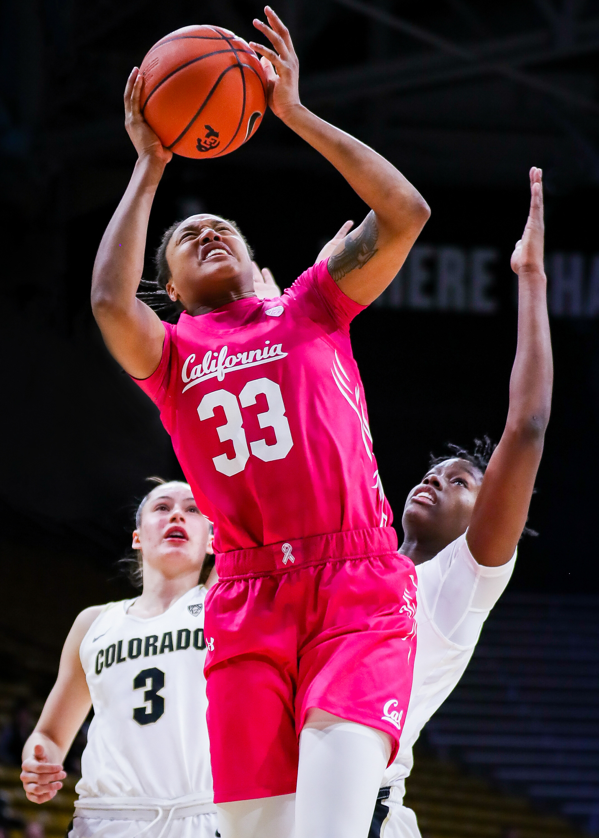 Jaelyn Brown #33 of the University of California Berkeley Golden Bears makes a layup past the defense of Emma Clarke #3 and Mya Hollingshed #21 of the University of Colorado Boulder Buffaloes at Gampel Pavillion in Boulder, Colorado. The Buffaloes defeated the Golden Bears 62-50.
