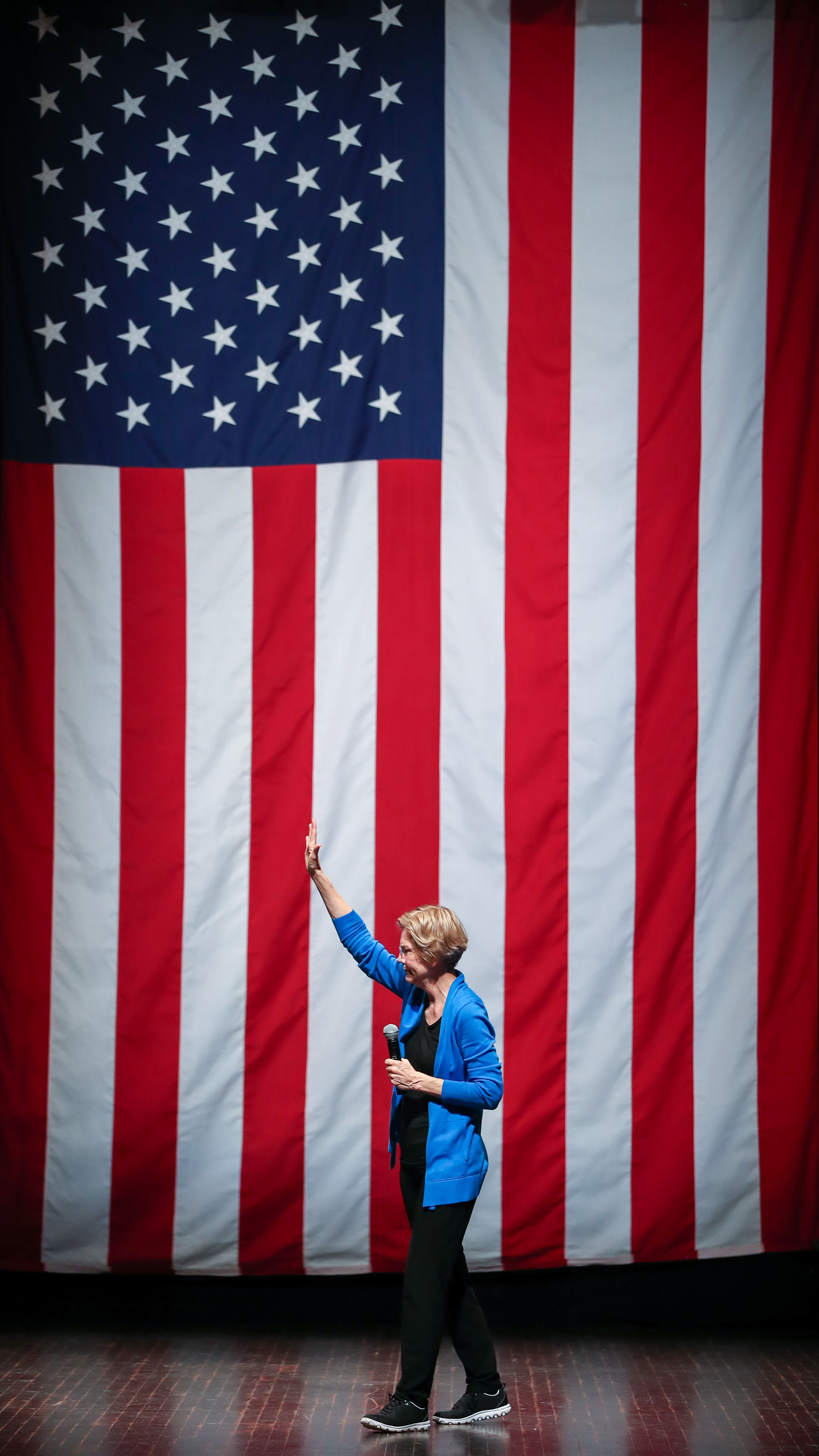 Senator Elizabeth Warren waves to the crowd in front of a large American flag during a town hall event on October 21, 2019 at Iowa State University in Ames, Iowa.