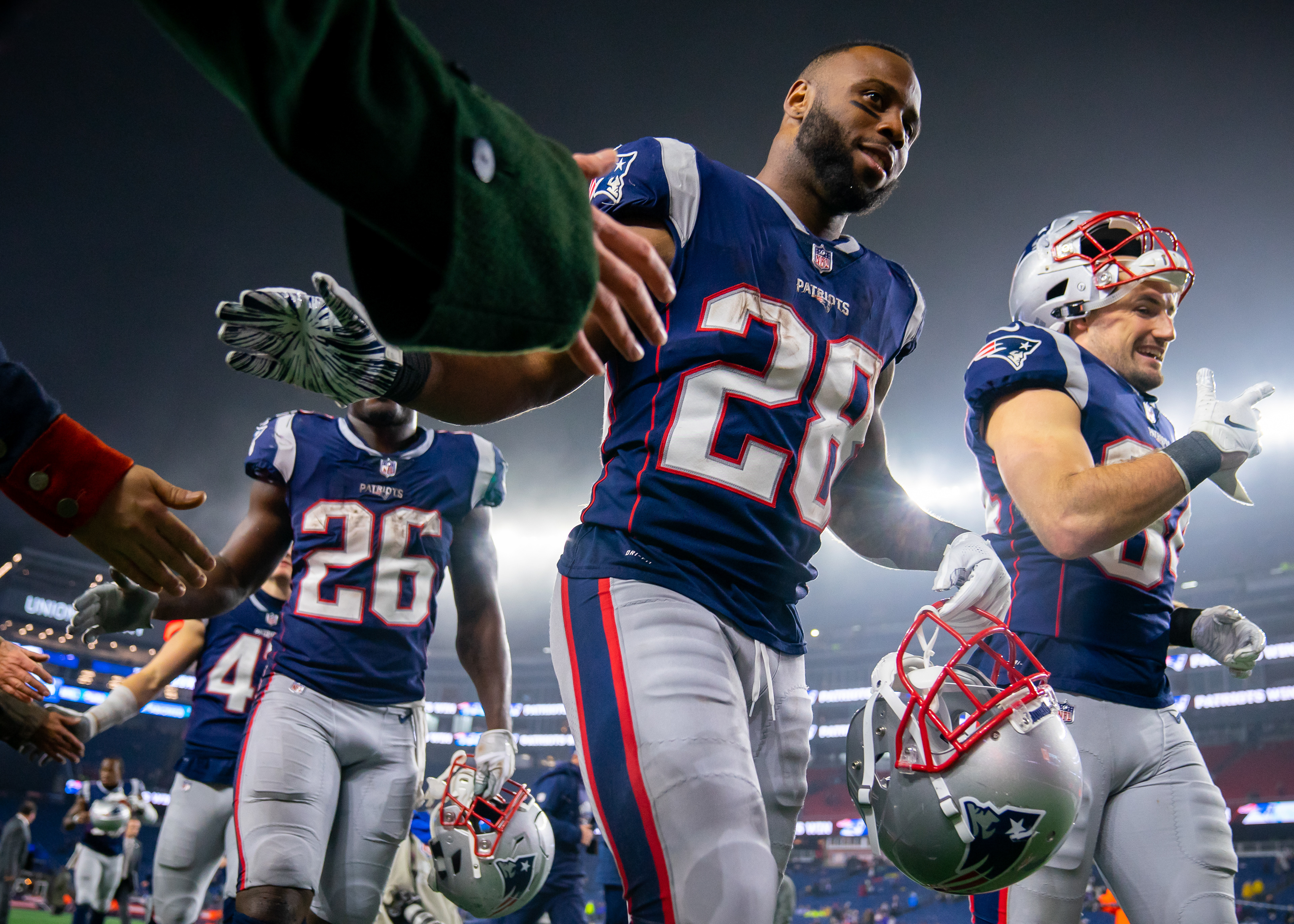 James White #28, Rex Burkhead #34, and Sony Michel #26 of the New England Patriots high-five members of the End Zone Militia after a game against the Minnesota Vikings on December 2, 2018 at Gillette Stadium in Foxborough, Massachusetts. The Patriots defeated the Vikings 24-10.