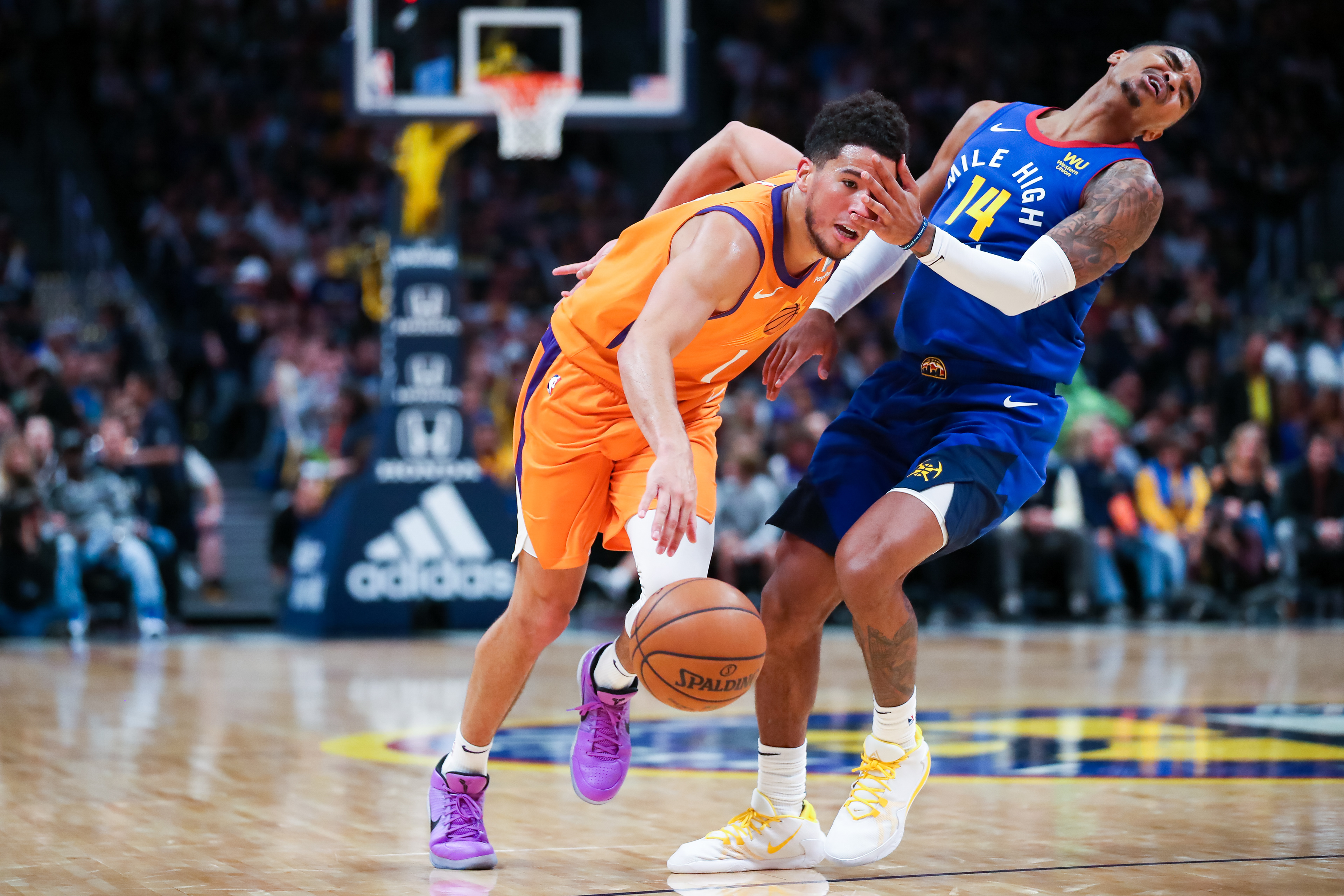 A foul is called against Gary Harris #14 of the Denver Nuggets as Devin Booker #1 of the Phoenix Suns moves past his defense during the third quarter at Pepsi Center on October 25, 2019 in Denver, Colorado.