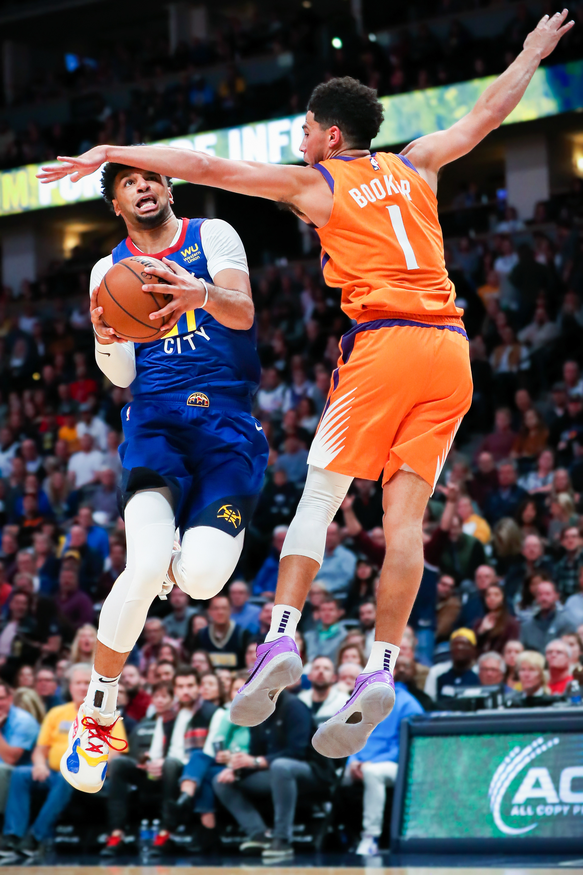 Jamal Murray #27 of the Denver Nuggets dunks past the defense of Devin Booker #1 of the Phoenix Suns during the second quarter at Pepsi Center on October 25, 2019 in Denver, Colorado.