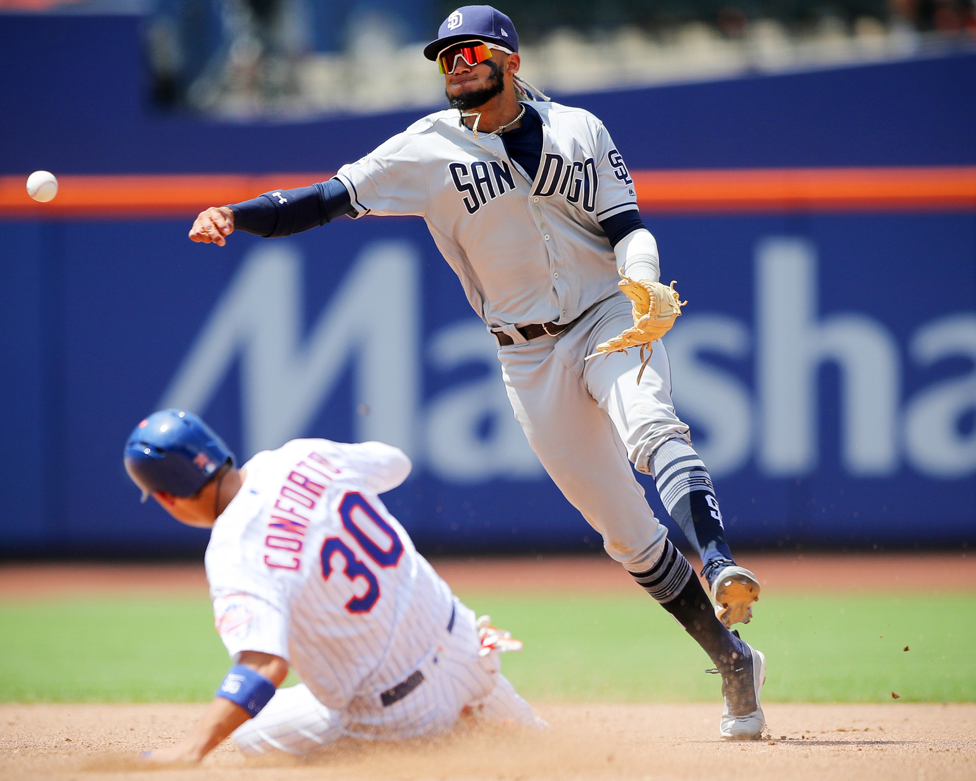 Fernando Tatis Jr. #23 of the San Diego Padres throws to first as Michael Conforto #30 of the New York Mets slides safely into second base at Citi Field on July 25, 2019 in Flushing, New York.