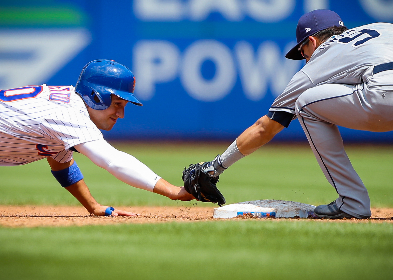 Luis Urias #9 of the San Diego Padres tags out Michael Conforto #30 of the New York Mets at second base at Citi Field on July 25, 2019 in Flushing, New York.
