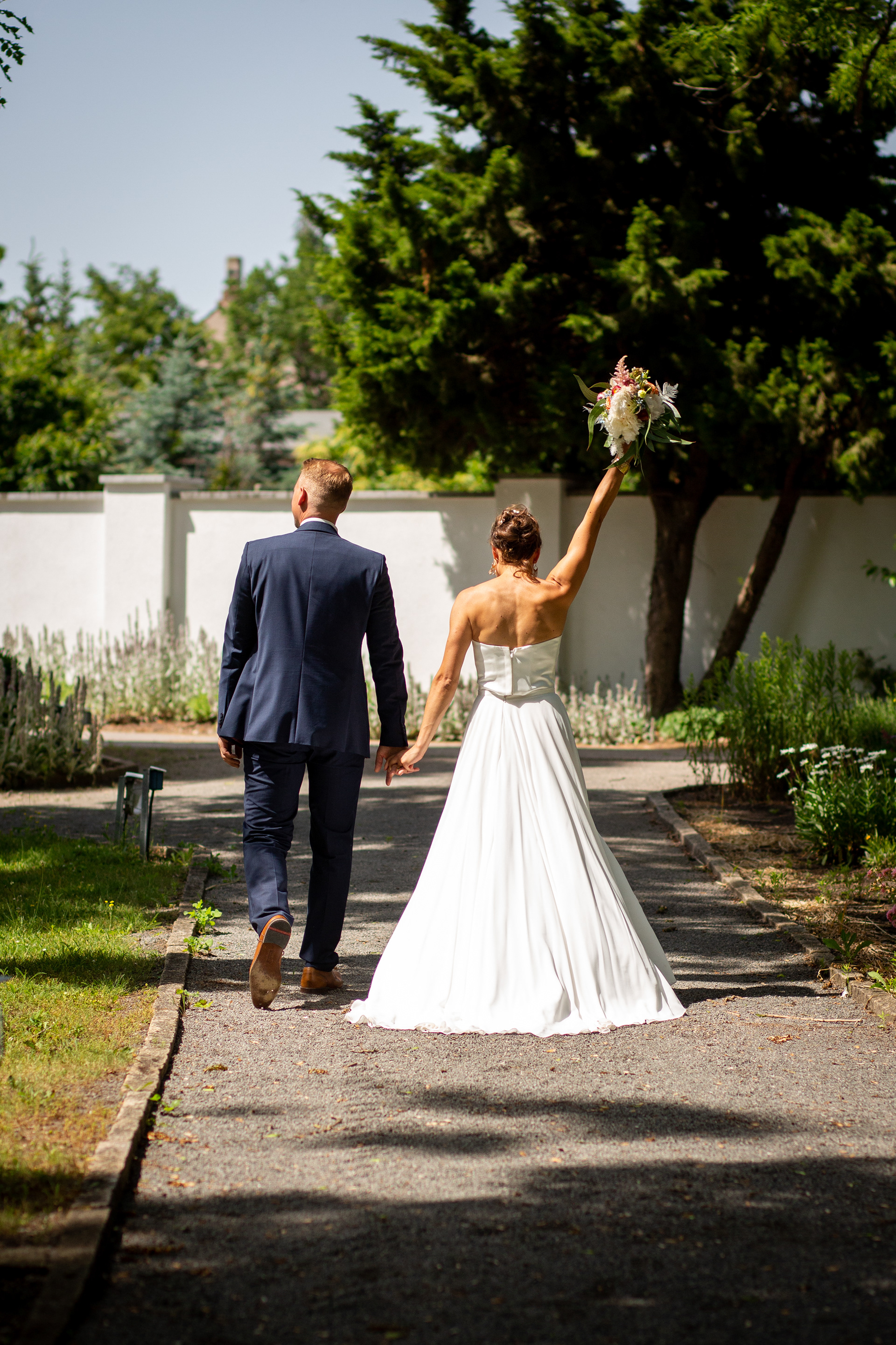 Hochzeit in Bahrendorf bei Magdeburg:Hochzeitspaar von Hinten fotografiert. Braut reckt Triumphierend den Brautstrauß in die Höhe..