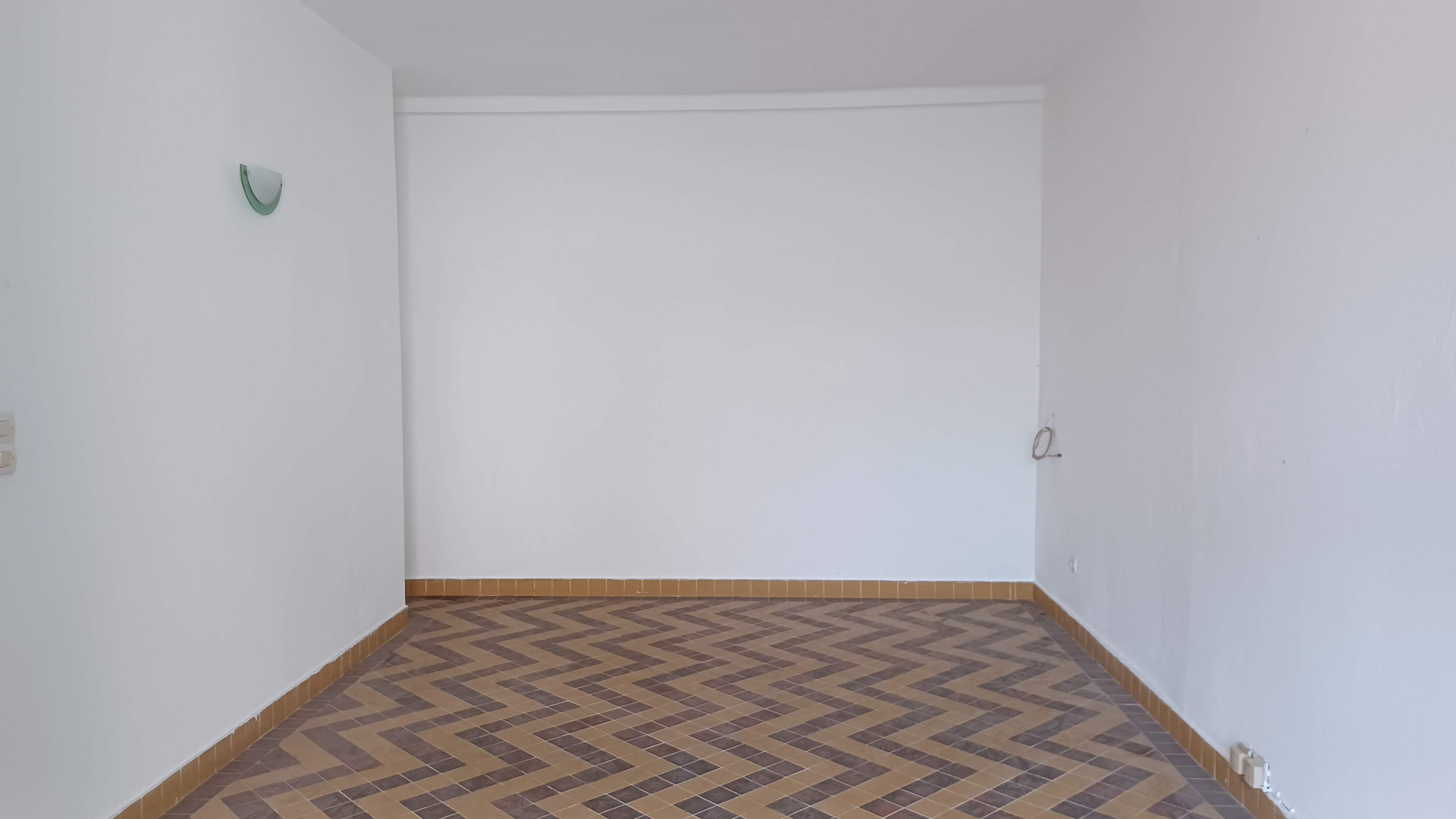 Une vue sur le fond de la pièce qui permet d'apprécier la luminostité et le carrelage en chevrons