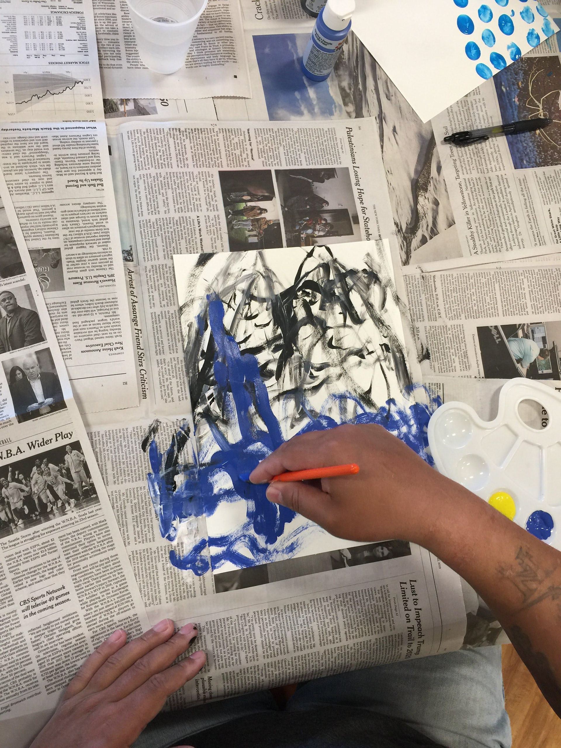 A resident who is visually impaired creates a painting of the ocean with the assistance of another resident.