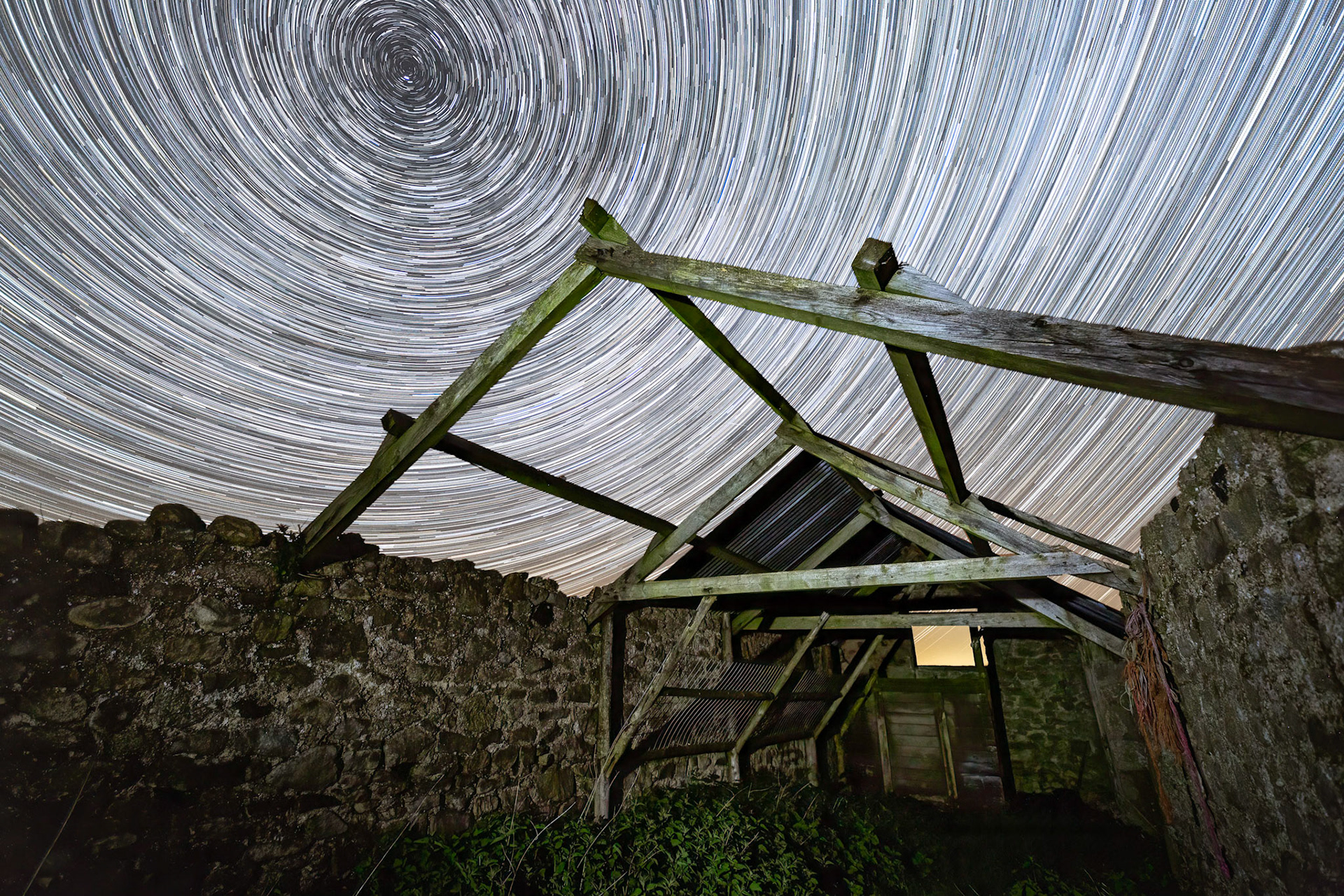 Thousands of stars circling over a the exposed truss or rafters of an abandoned stone barn on the edge of Bellever Woods.