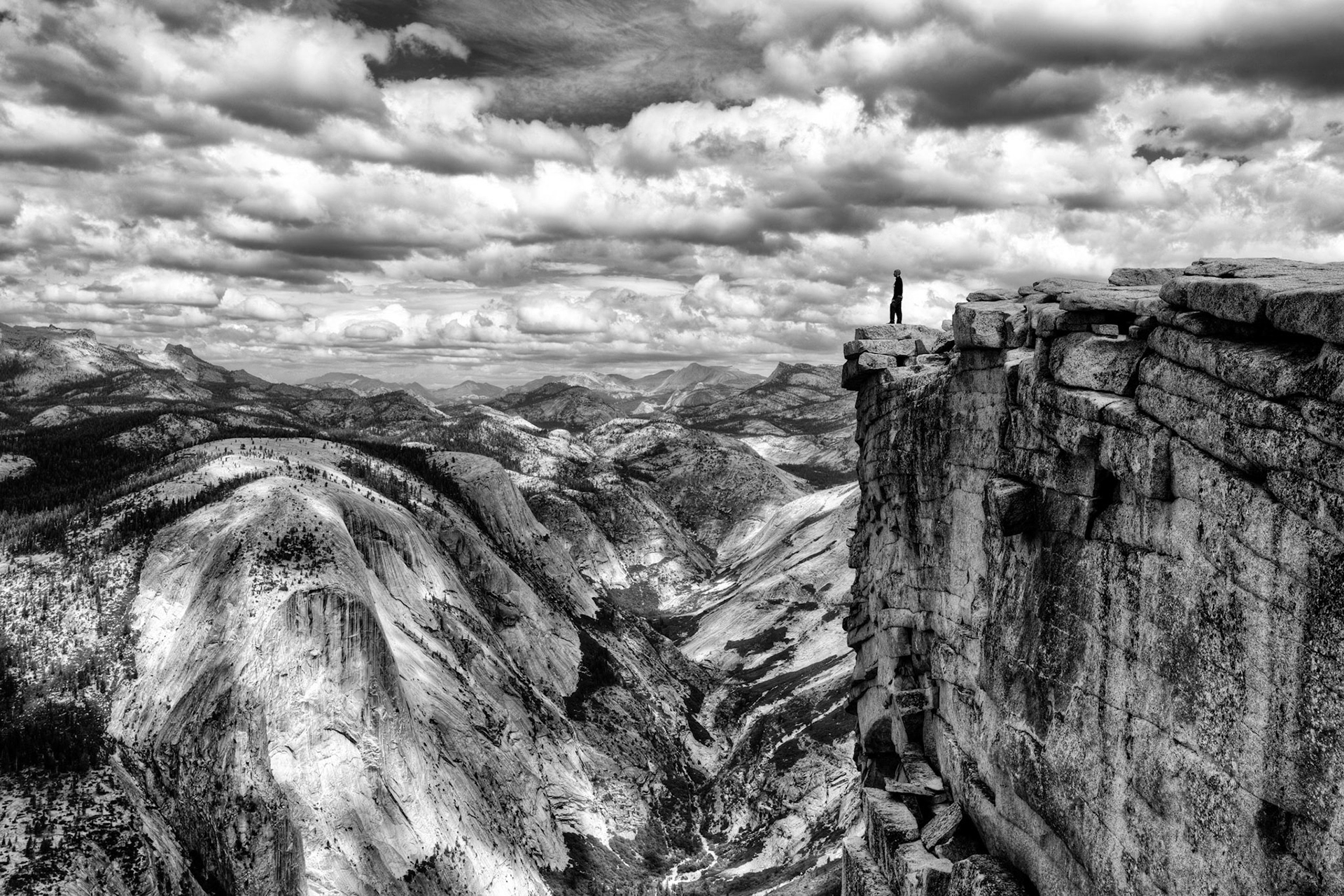 Hiker looking out across the Sierra Nevada Mountain range from the top of Half Dome.