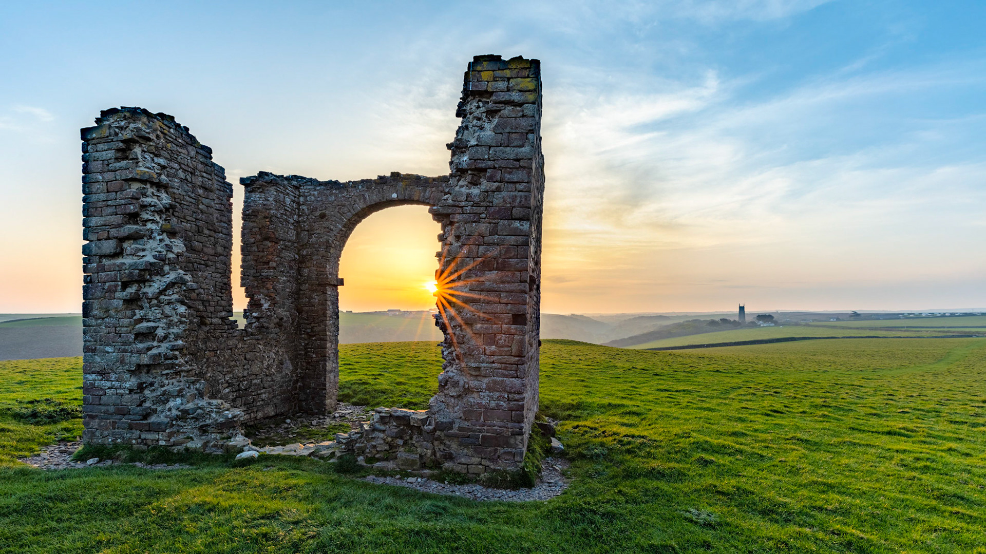Sunrising over the North Devon hills and the sun bursting on an old abandoned folley with the village of Stoke in the distance.