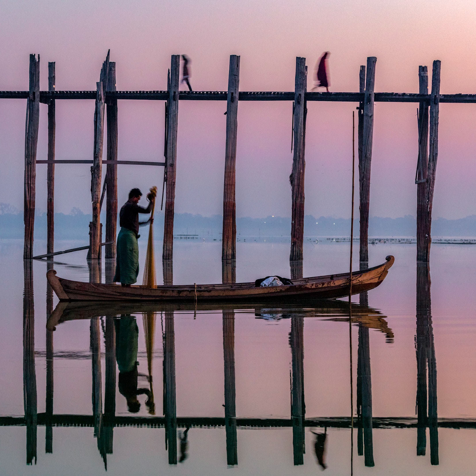 Local Burmese fisherman preparing his net in order to be thrown on the Taung Tha Man Lake with U Bein Bridge in Amarapura, Myanmar.