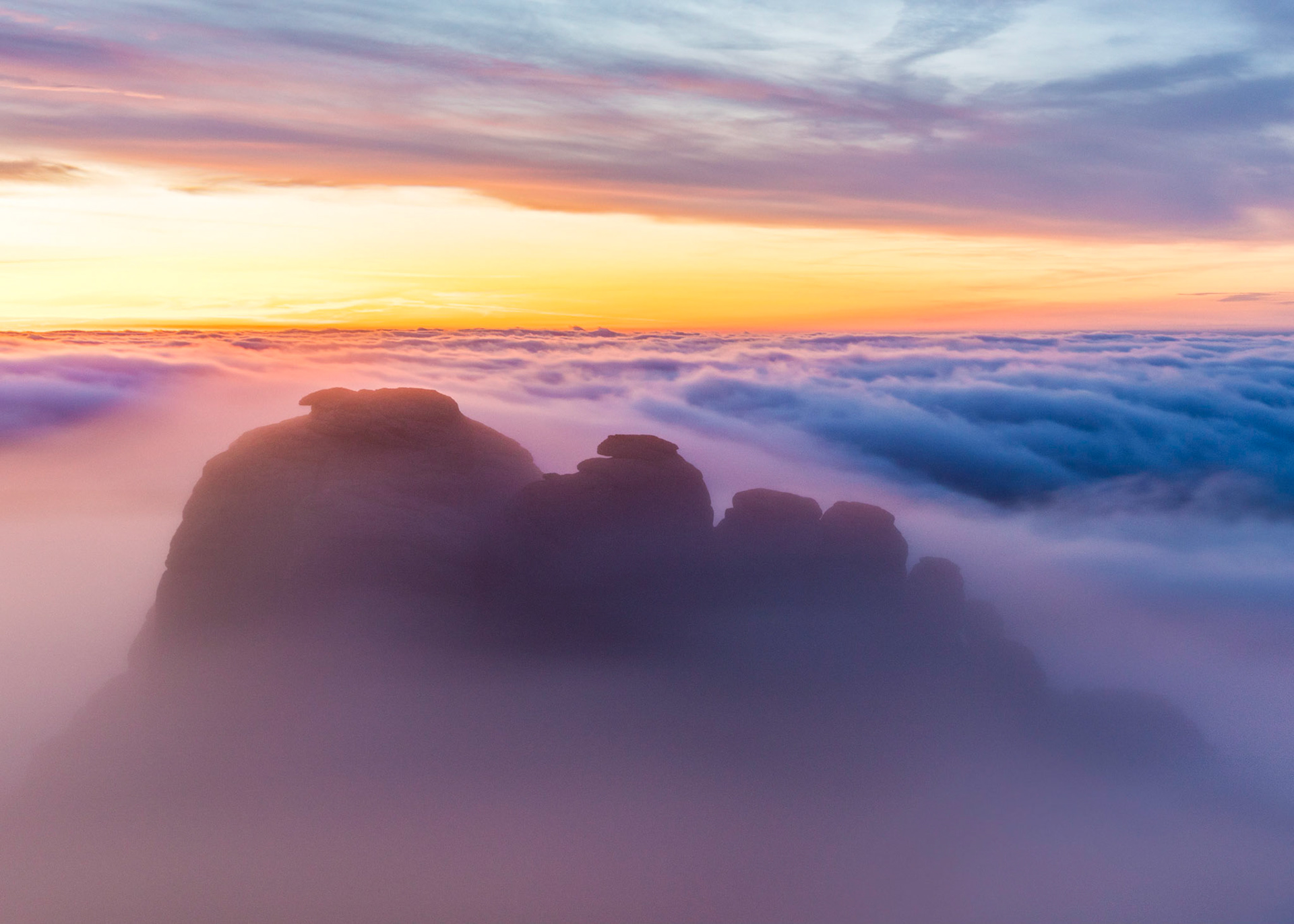 Haytor rocks emerging from the low lying clouds just before sunrise in Dartmoor National Park, Devon, England.