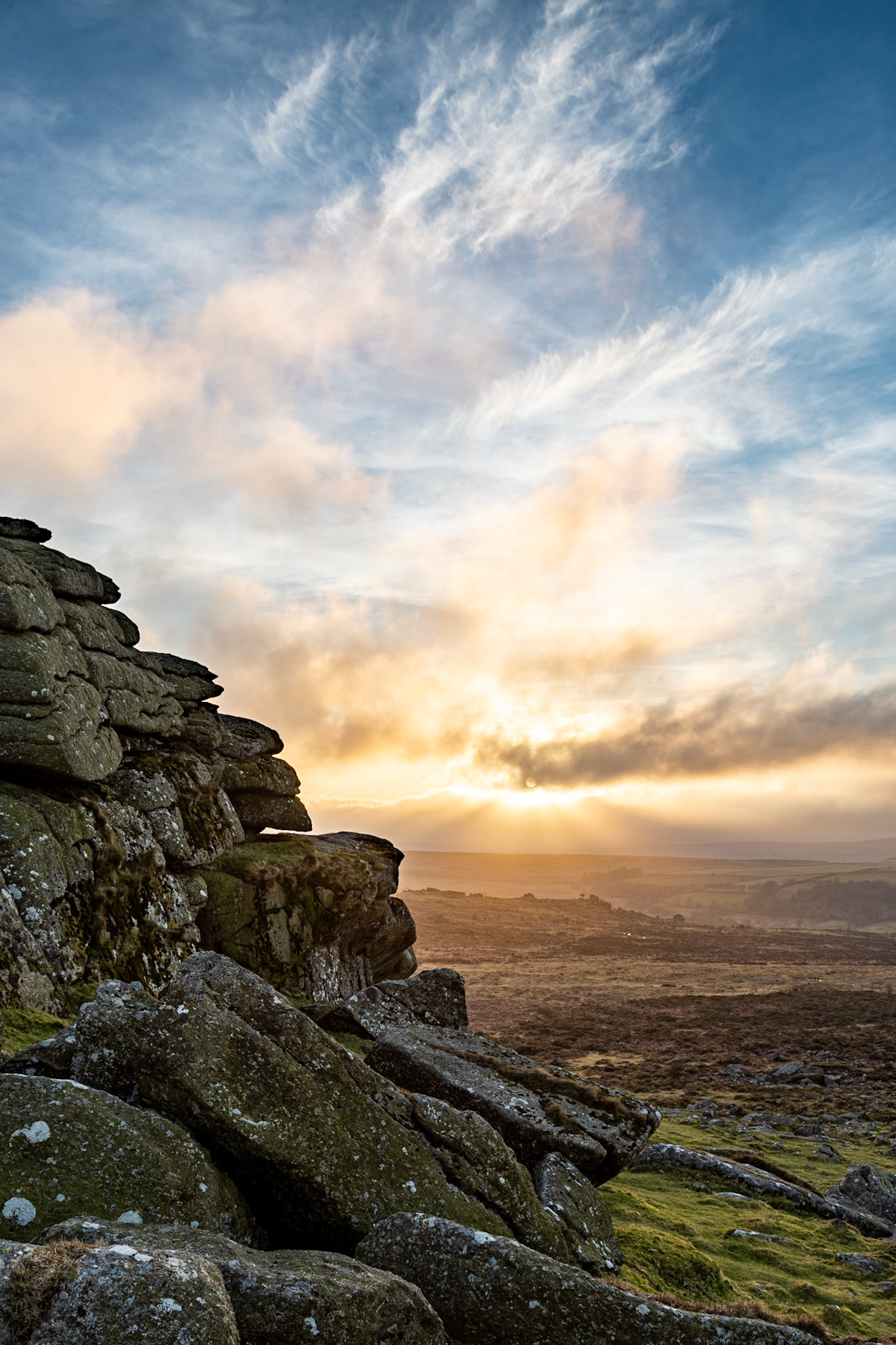 The late evening sun breaking through the clouds near Haytor Rocks in Dartmoor National Park.