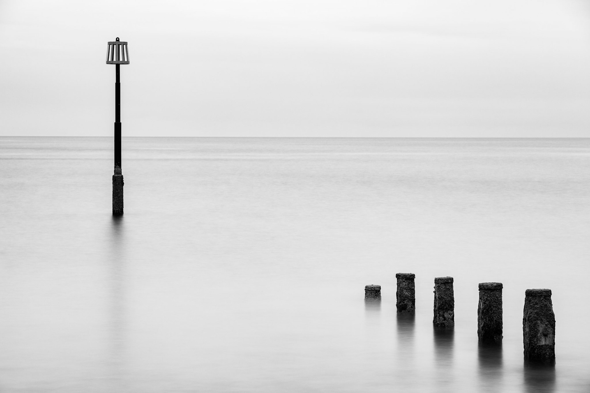 Long of a few groynes and a marker in the sea near Teignmouth, Devon.