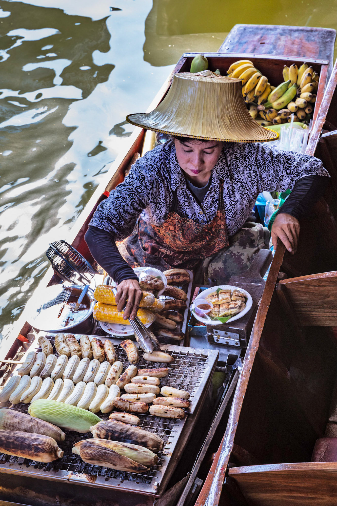 Woman turning bananas on her boat at a floating market