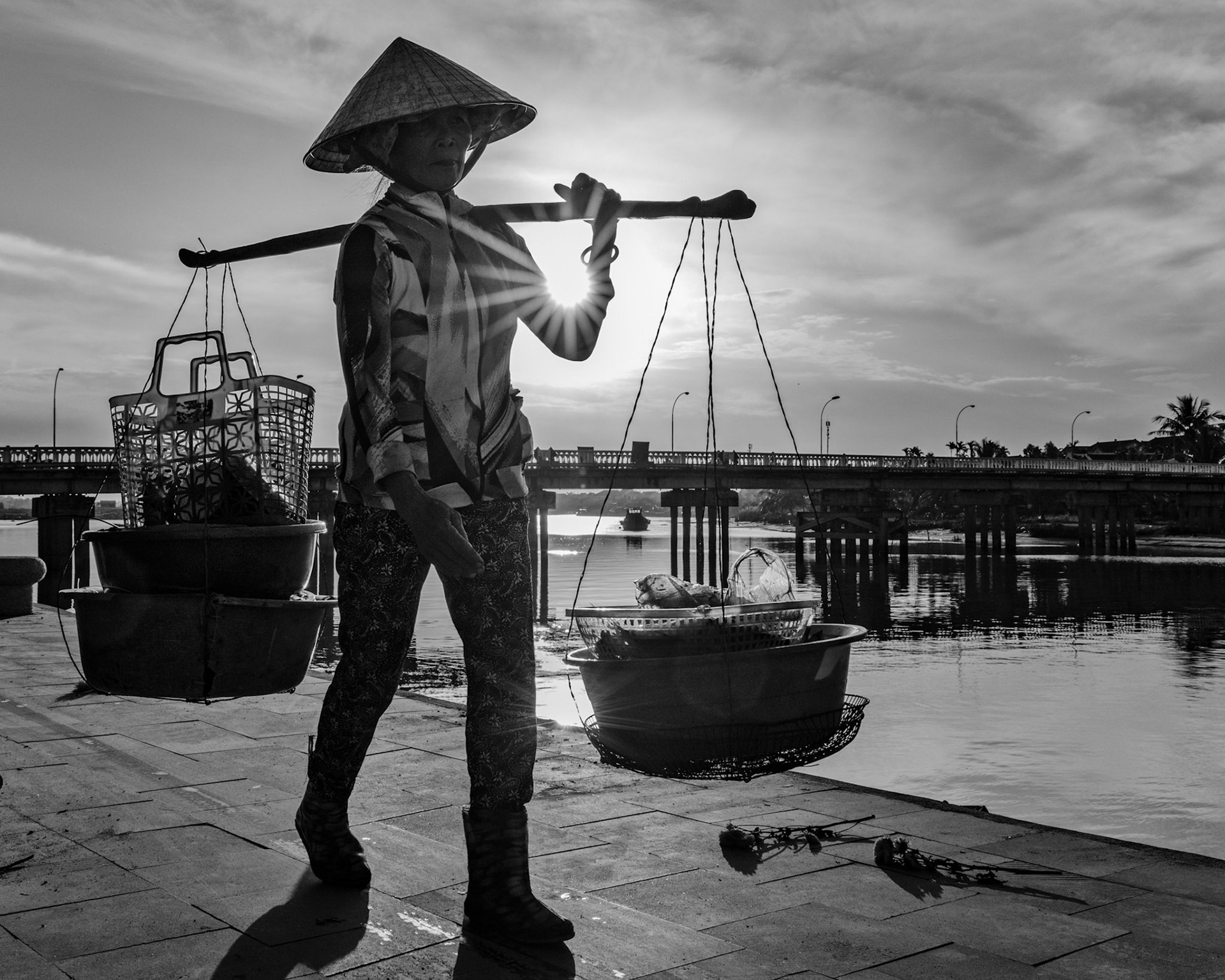 Woman carrying baskets on the river side in Hoi An