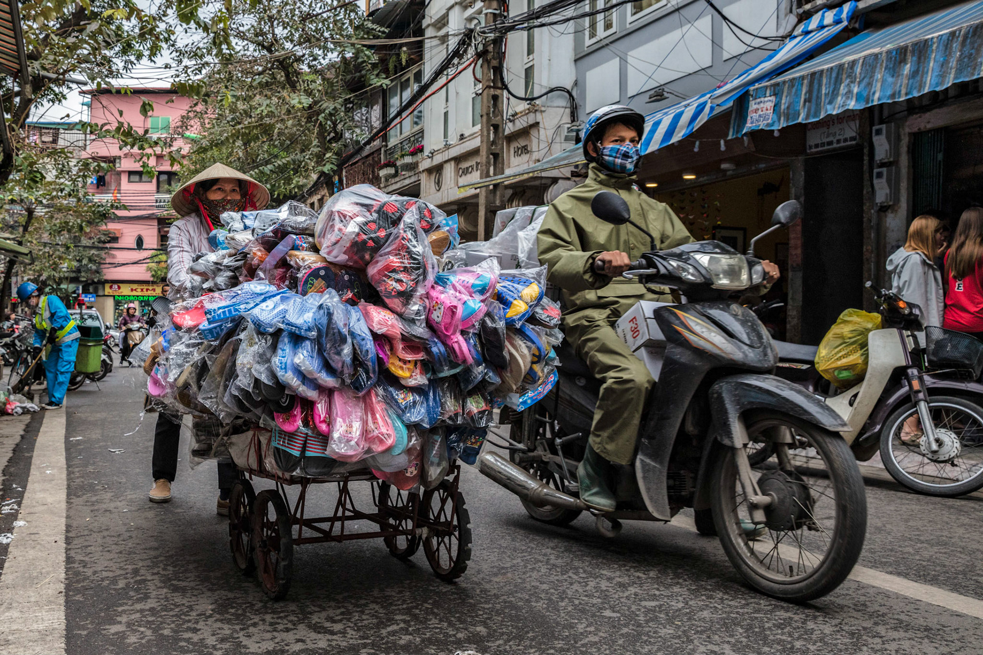 The streets of Hanoi busy with scooters and people selling various items.