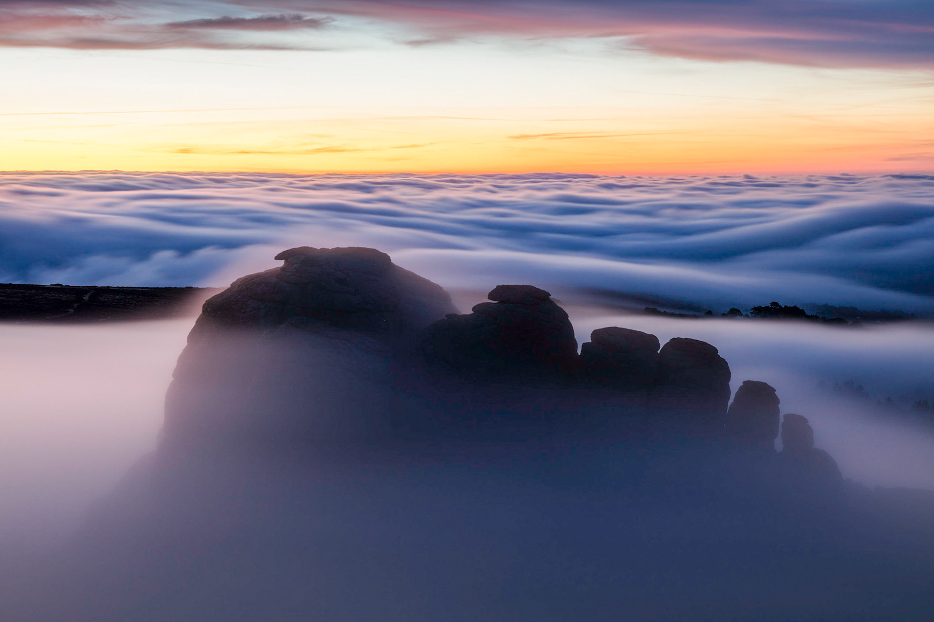 Haytor rocks emerging from the low lying clouds during blue hour in Dartmoor National Park, Devon, England.